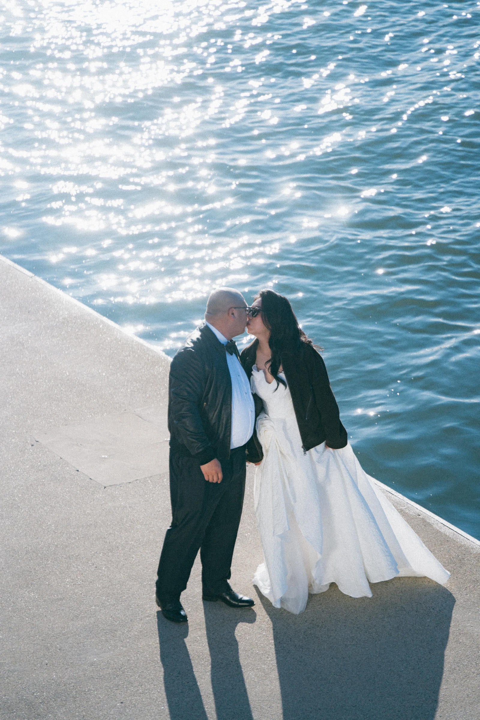 Couple kissing beside the sparkling river, seen from above.