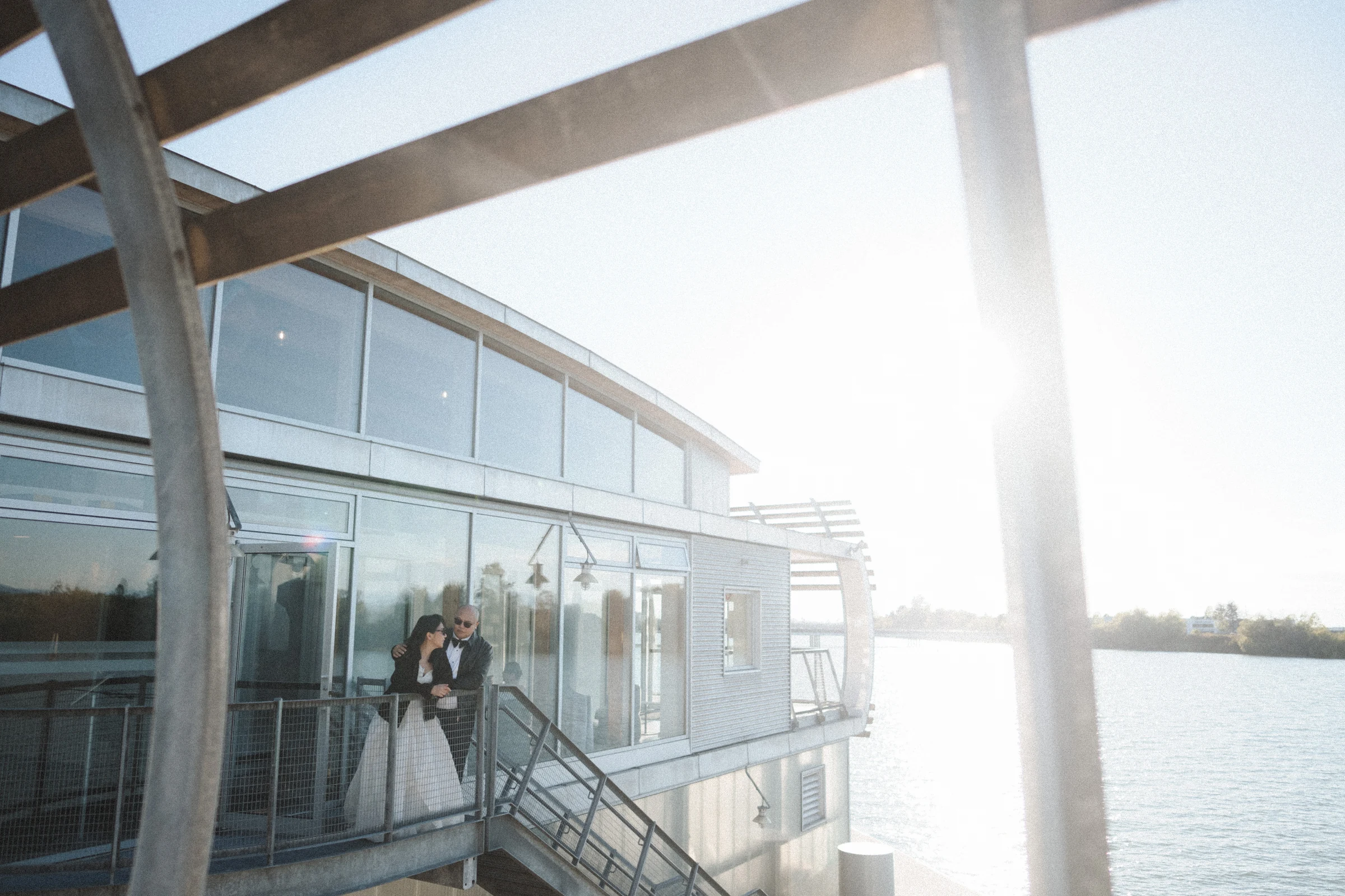 Couple on the upper balcony with the sun shining behind the building.