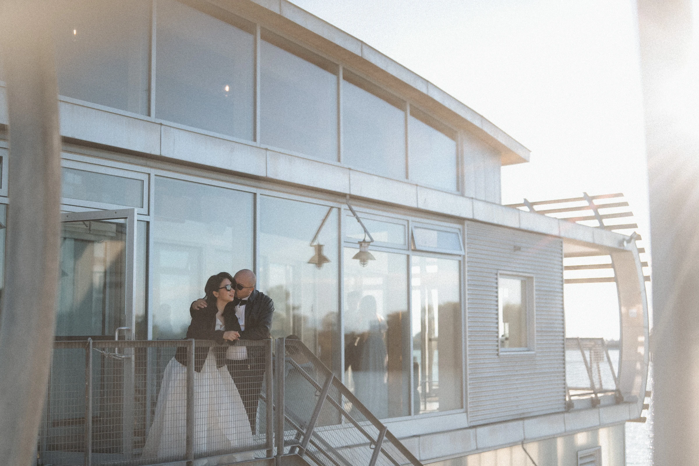 Guests leaning together on the upper boathouse balcony.