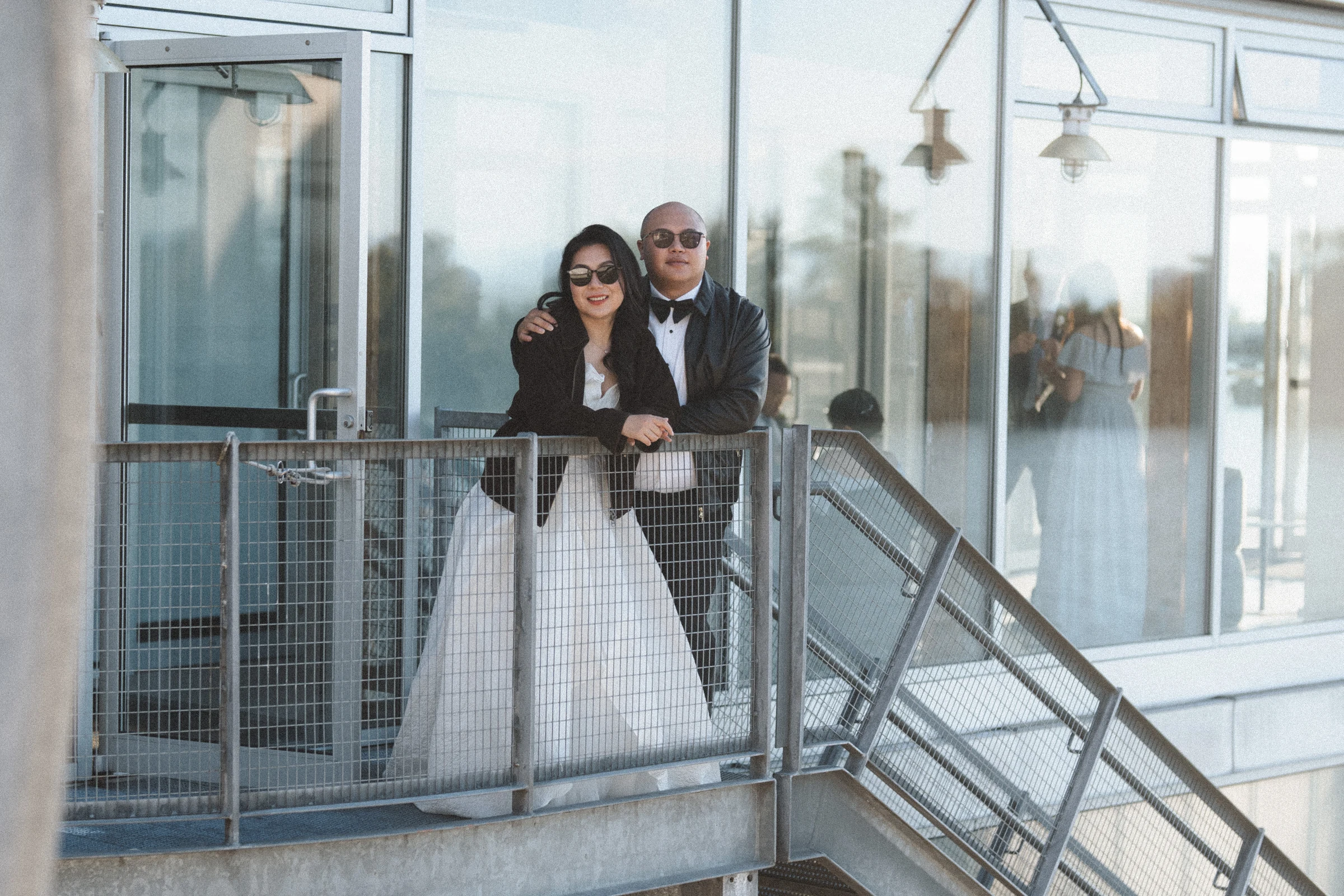 Bride and guests smiling beside the upper balcony railings.