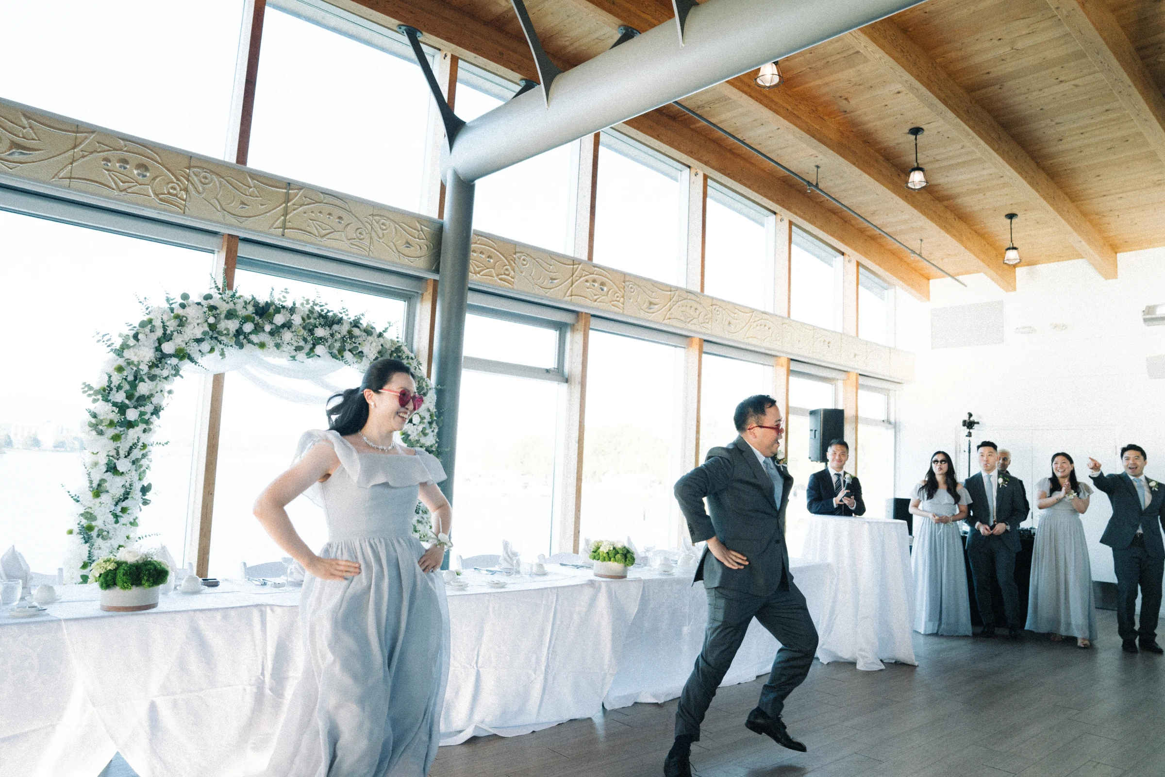Bride and groom entering the reception with their arms extended in a playful dance.