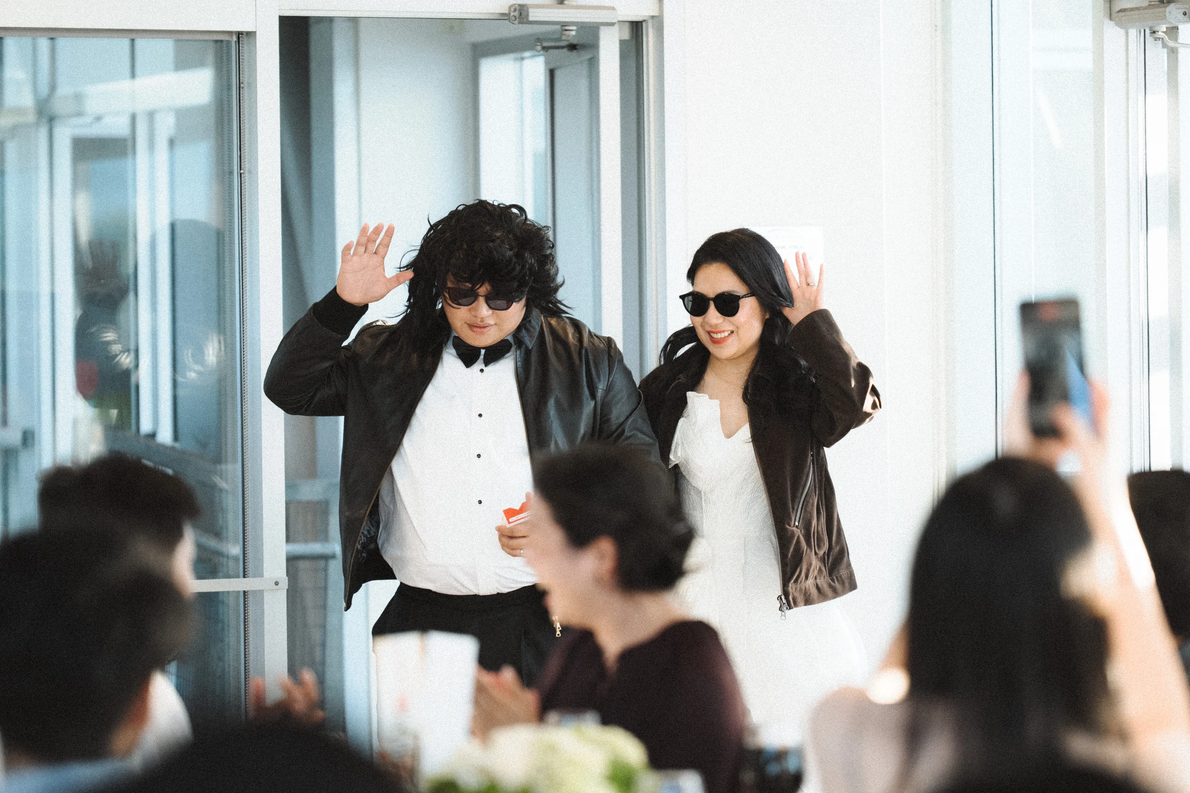 Two guests in sunglasses entering the reception together.