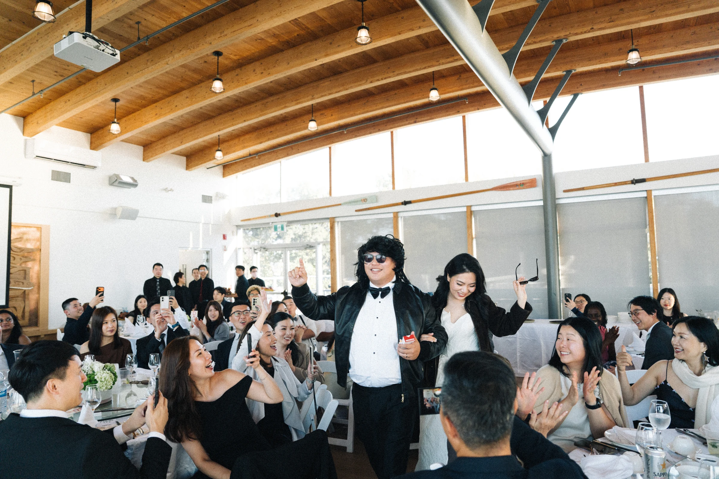 Wedding party members making a lively entrance beneath the timber ceiling.