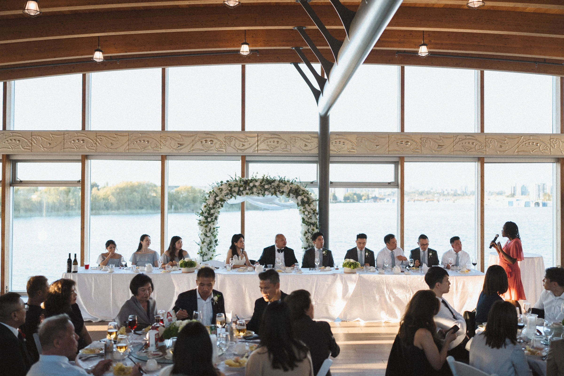Wide view of the reception hall, tables and river-facing windows.