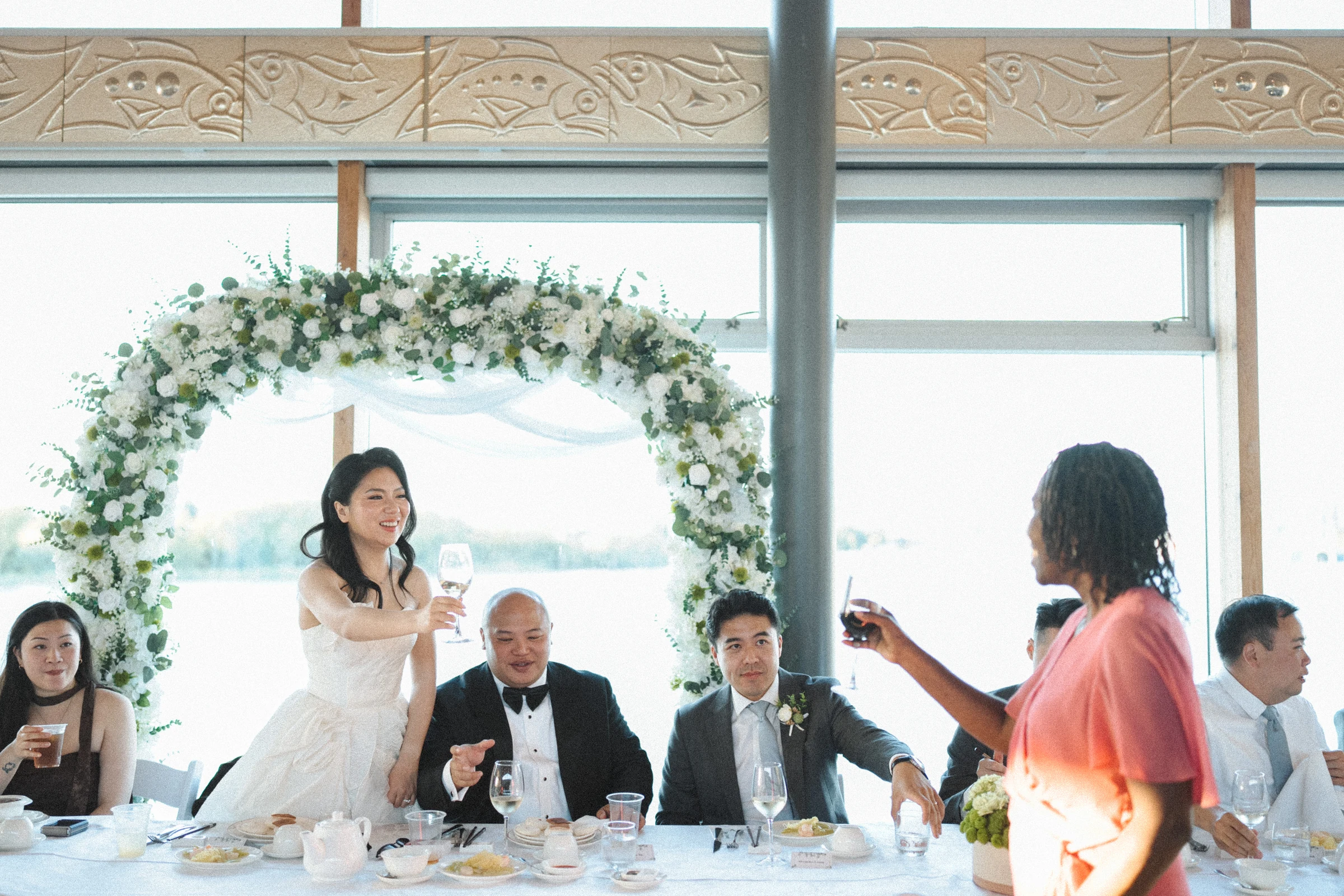 Guest speaking to the couple beside the reception flower arch.