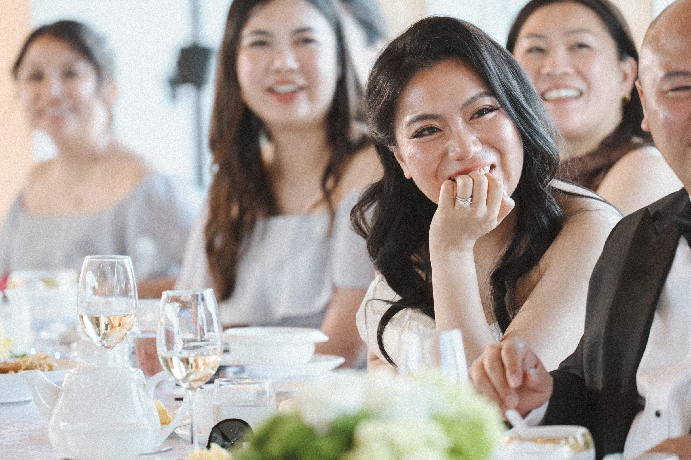 Close view of the bride smiling with a hand near her mouth.