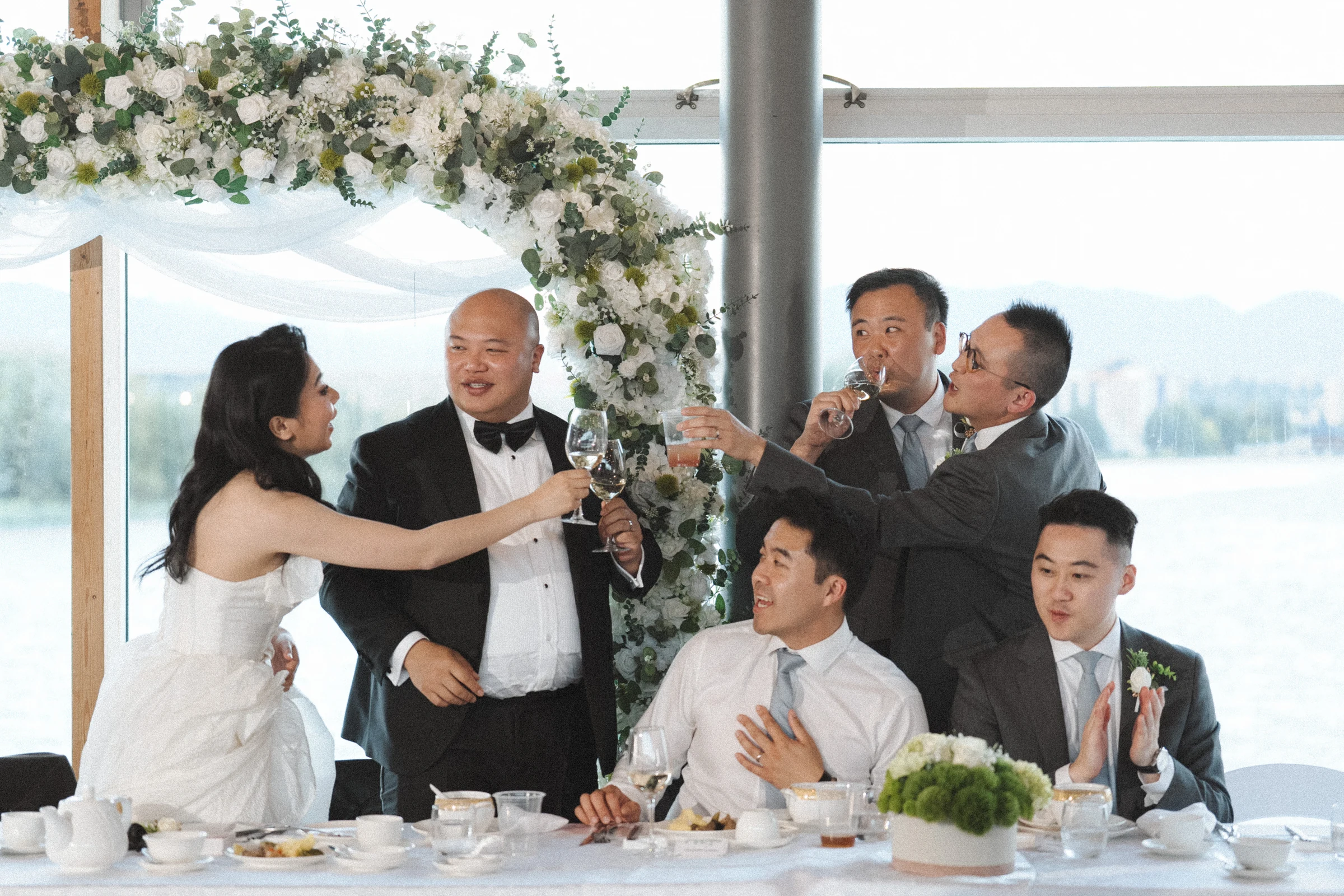 Bride raising a microphone beside the groom and their reception guests.