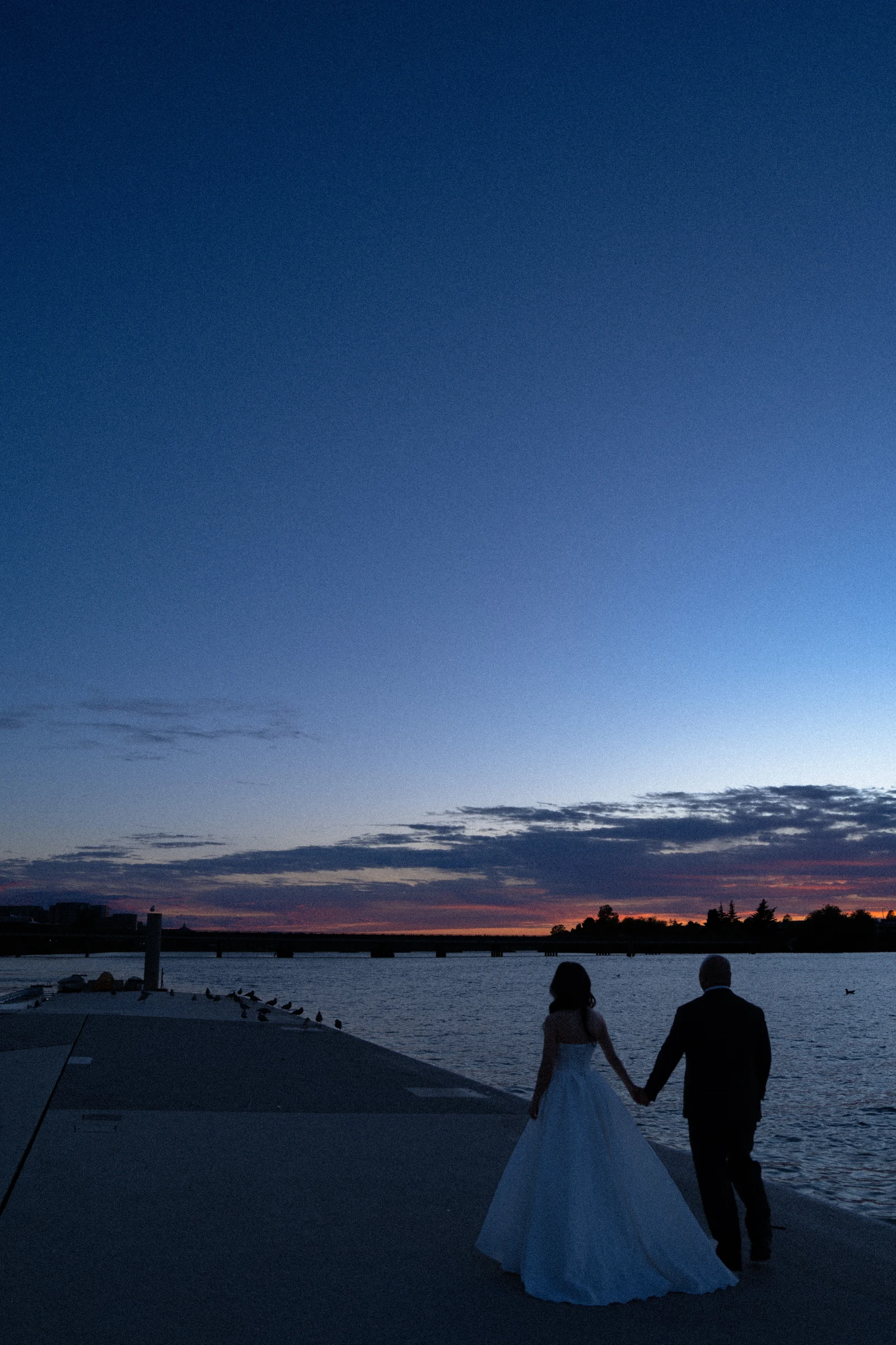 Tall dusk portrait of the couple by the Fraser River.