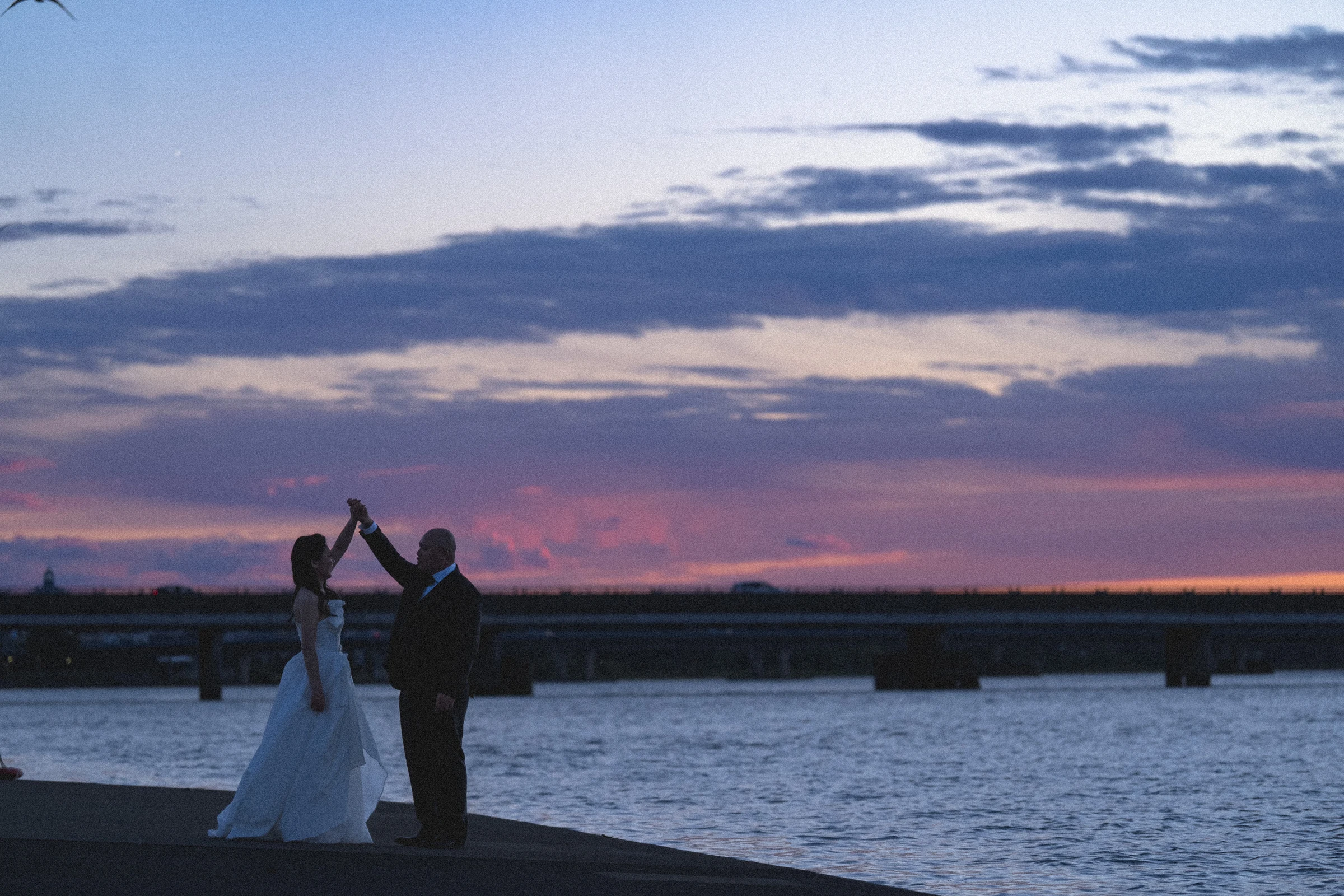Couple raising their joined hands beneath the evening sky.