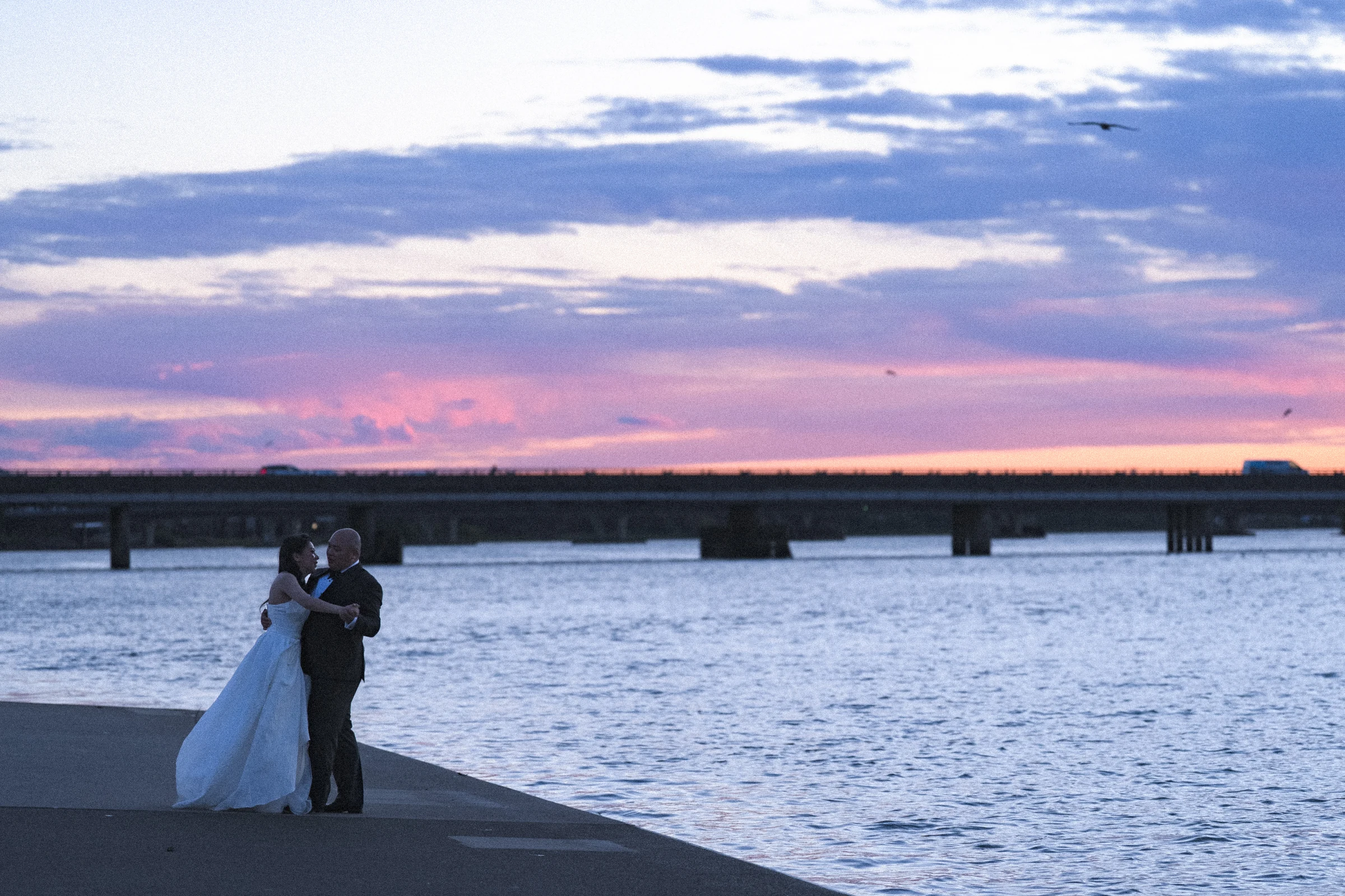 Couple embracing by the river as the evening light fades.