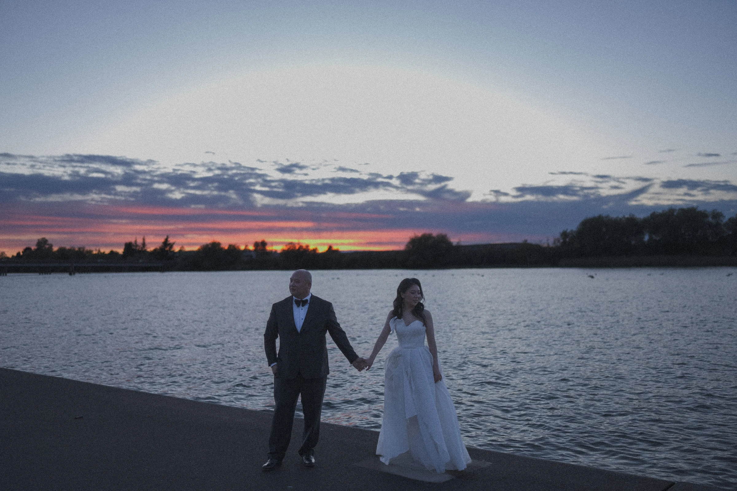 Couple facing the camera on the waterfront deck in the fading light.