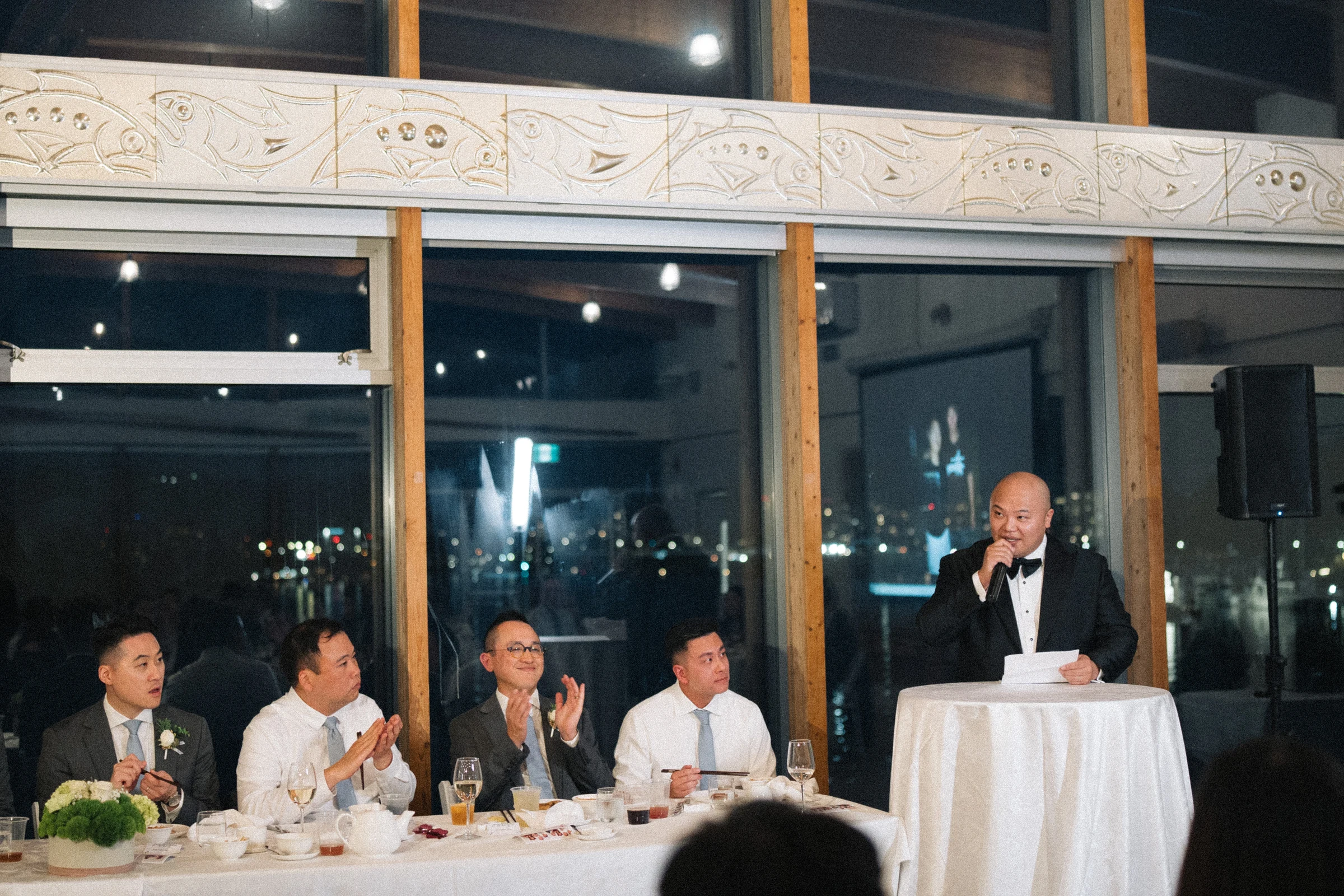 Guest speaking at the reception with the couple seated beside him.