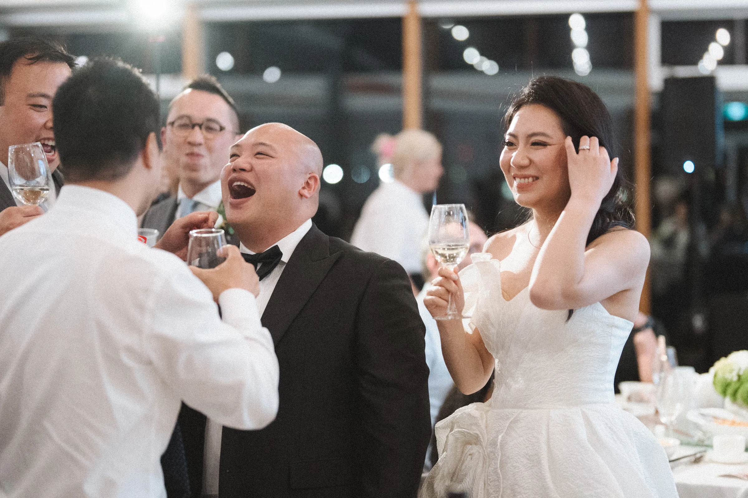 Groom laughing with guests during a reception toast.