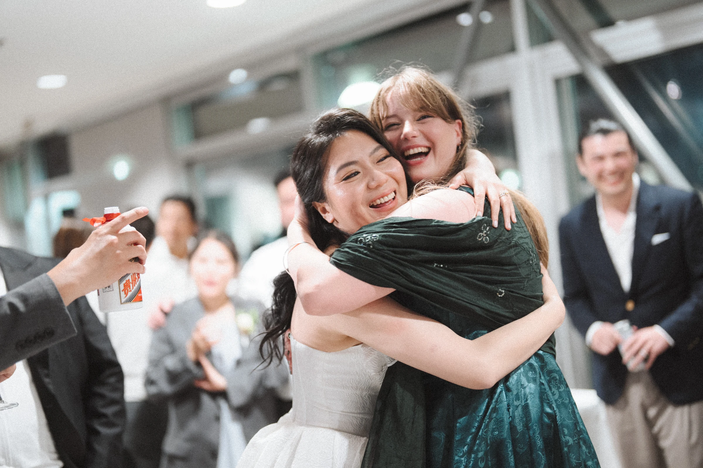 Bride sharing a close hug with a guest beside the dance floor.