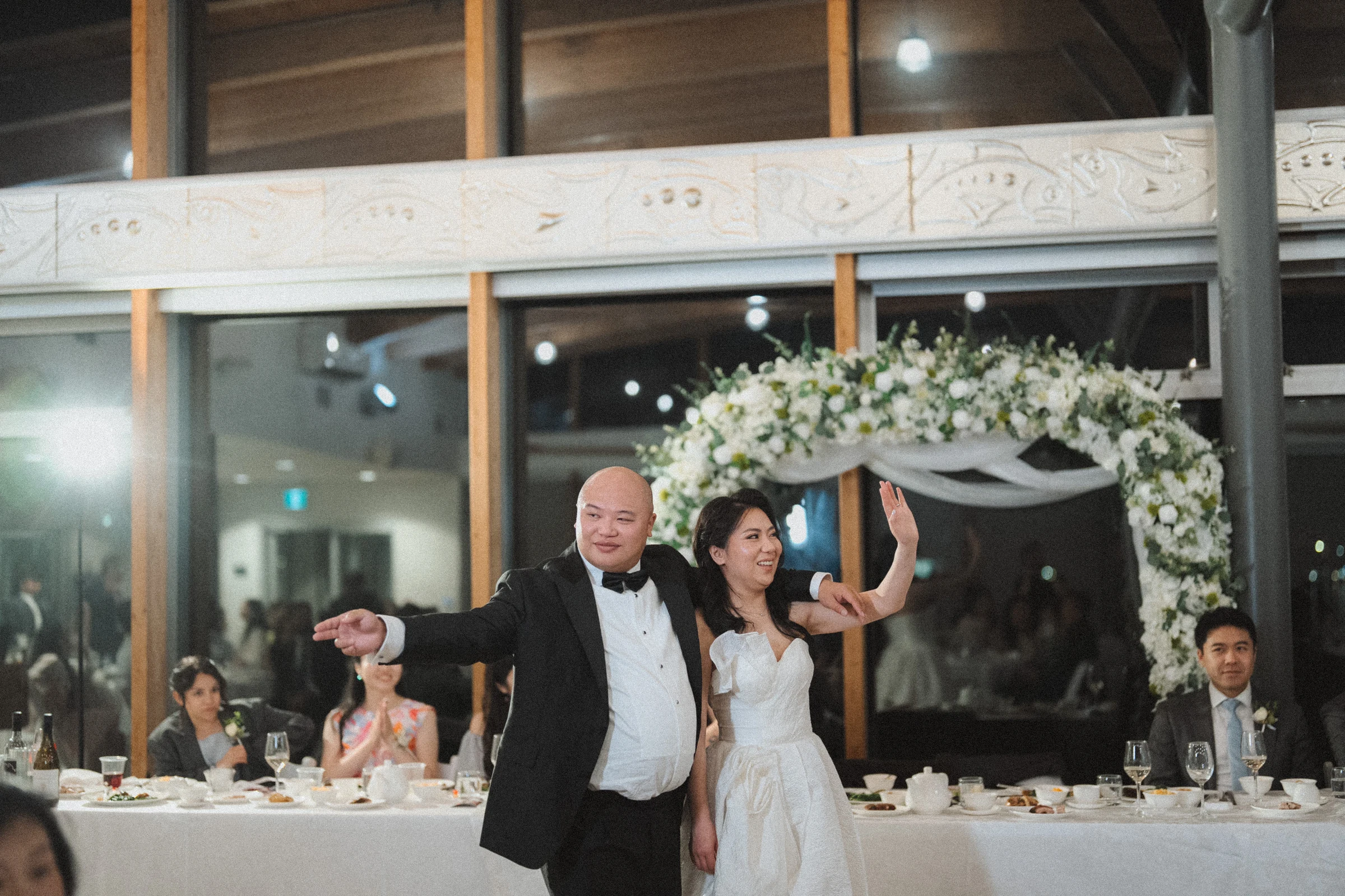 Couple raising their arms in front of the reception tables.