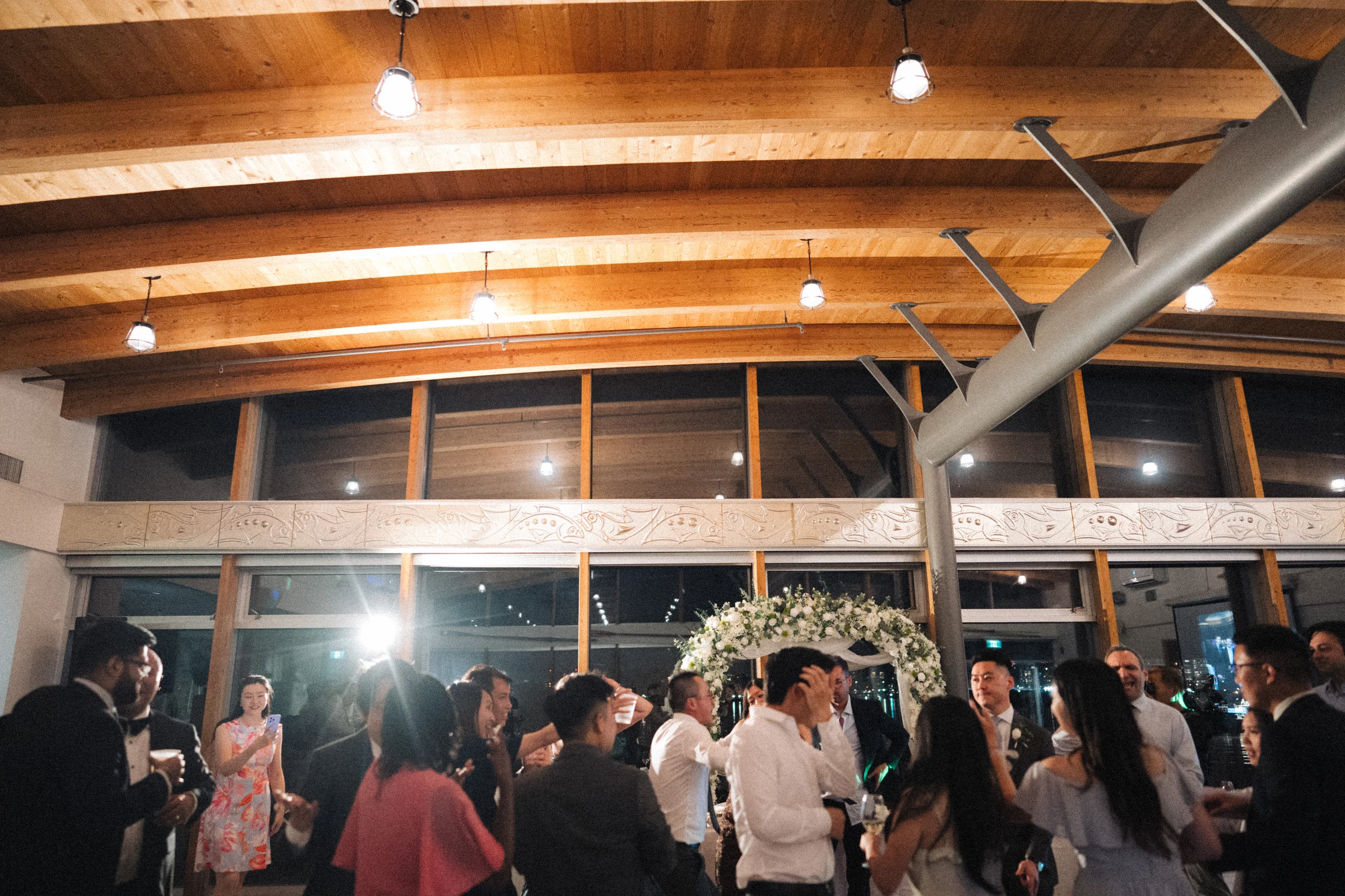 Wide view of the final dance-floor celebrations beneath the boathouse ceiling.