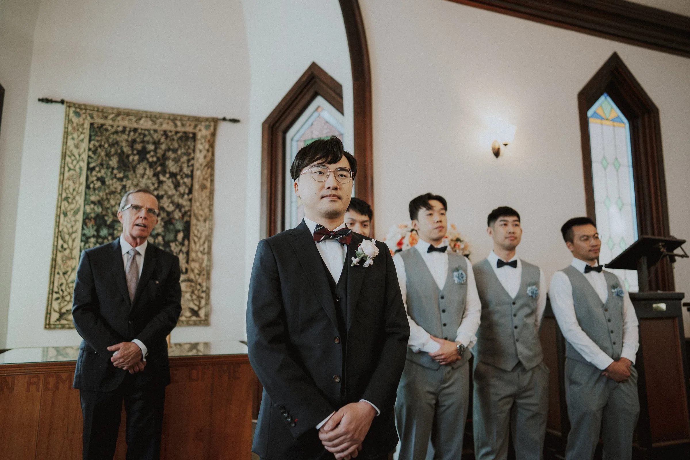 Groom waiting at the front of the chapel beside the wedding party.