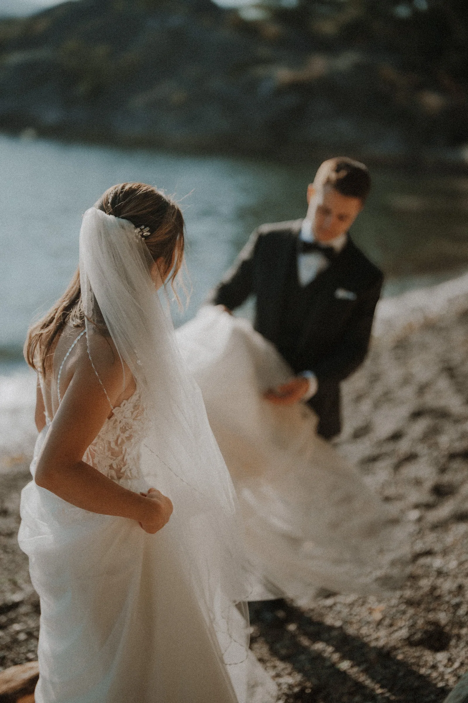 Bride glancing back while the groom lifts the train of her gown.