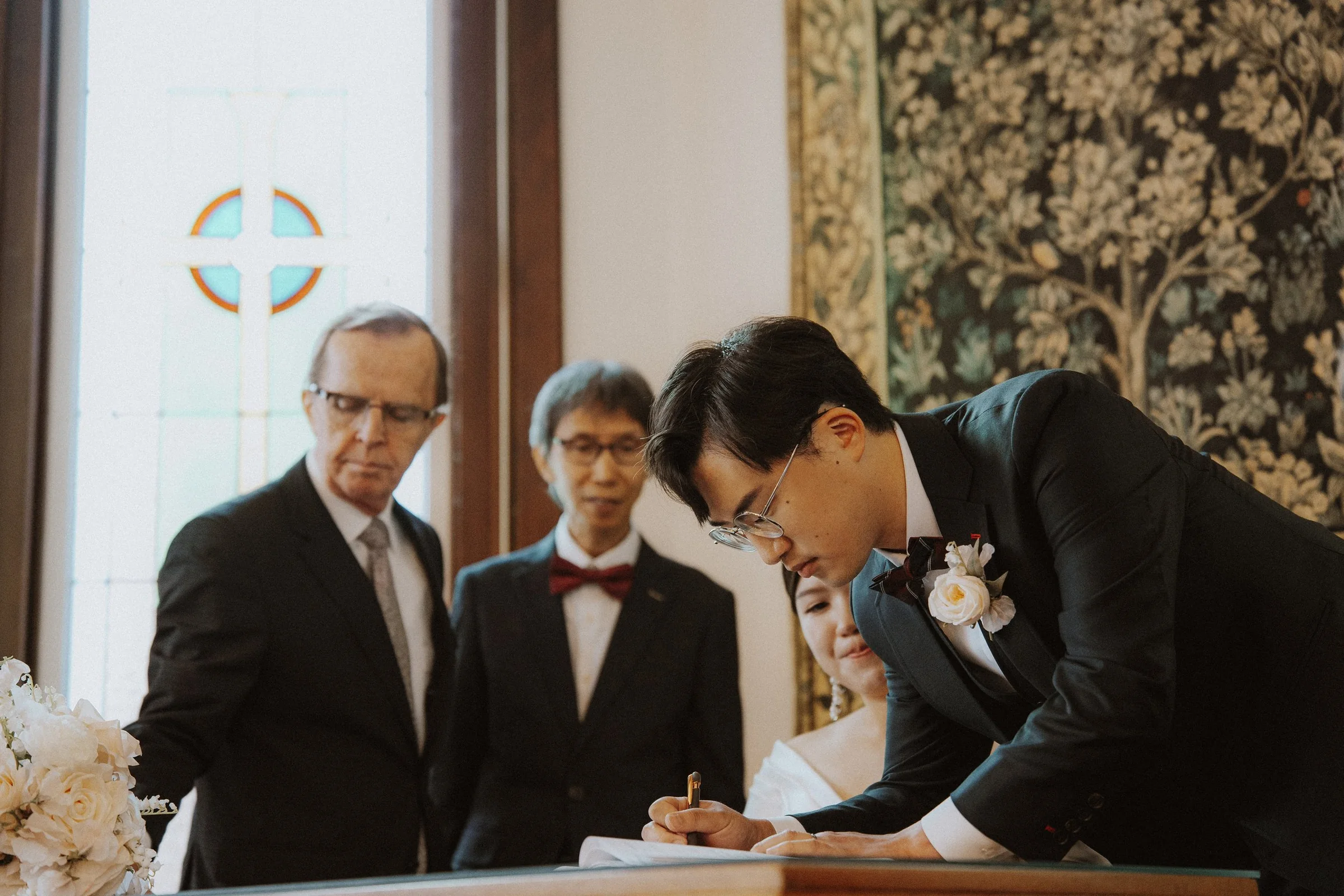 Groom signing wedding documents at a table inside the chapel.