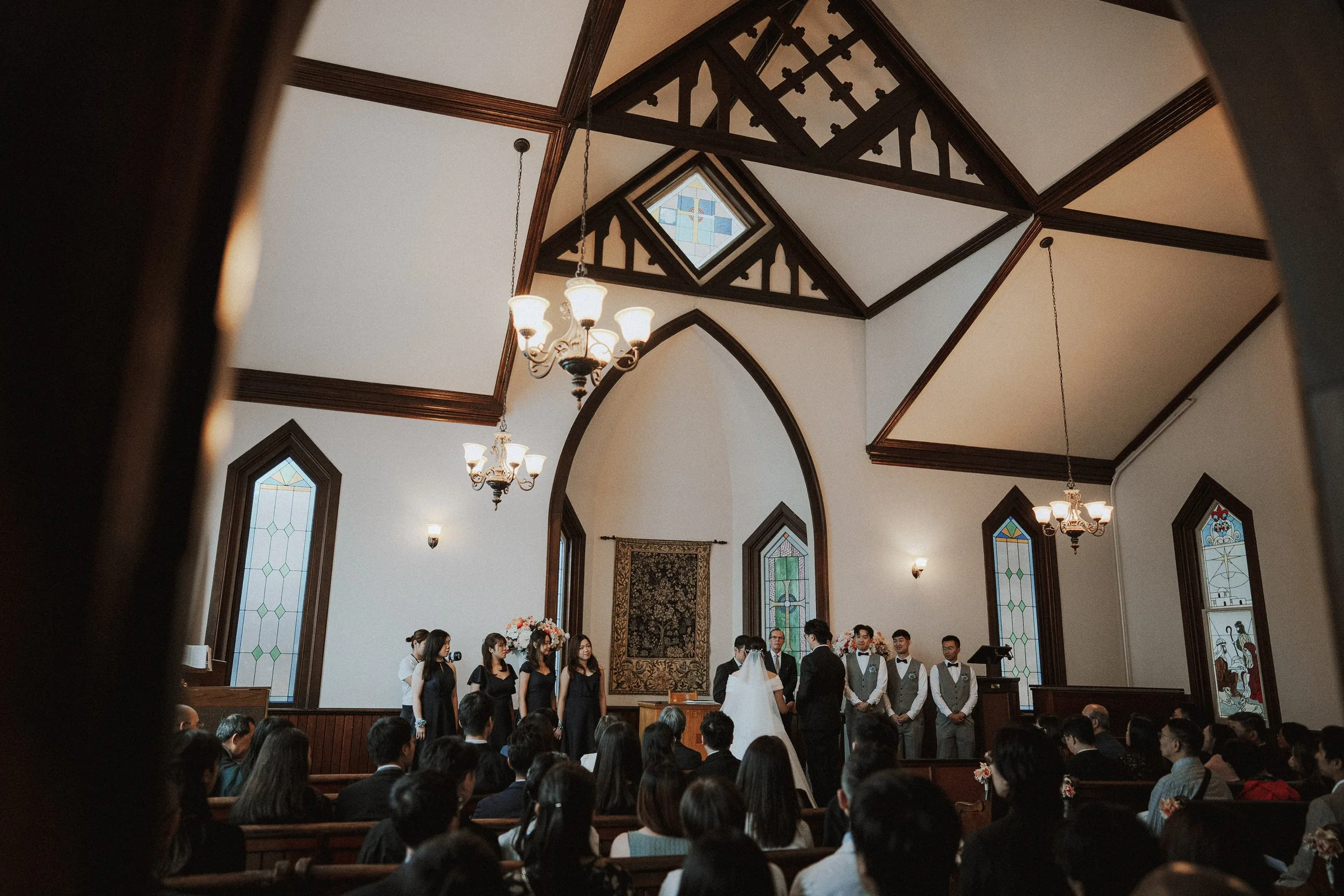 Wedding ceremony inside Minoru Chapel, couple at altar, dramatic lighting.