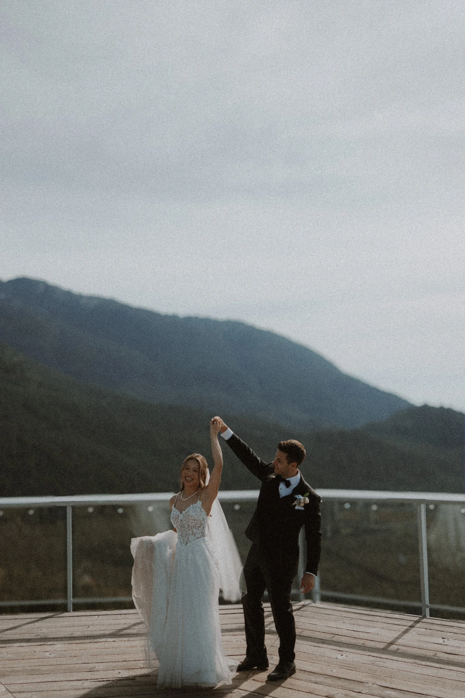Wide portrait of the bride and groom dancing on the timber viewing platform.