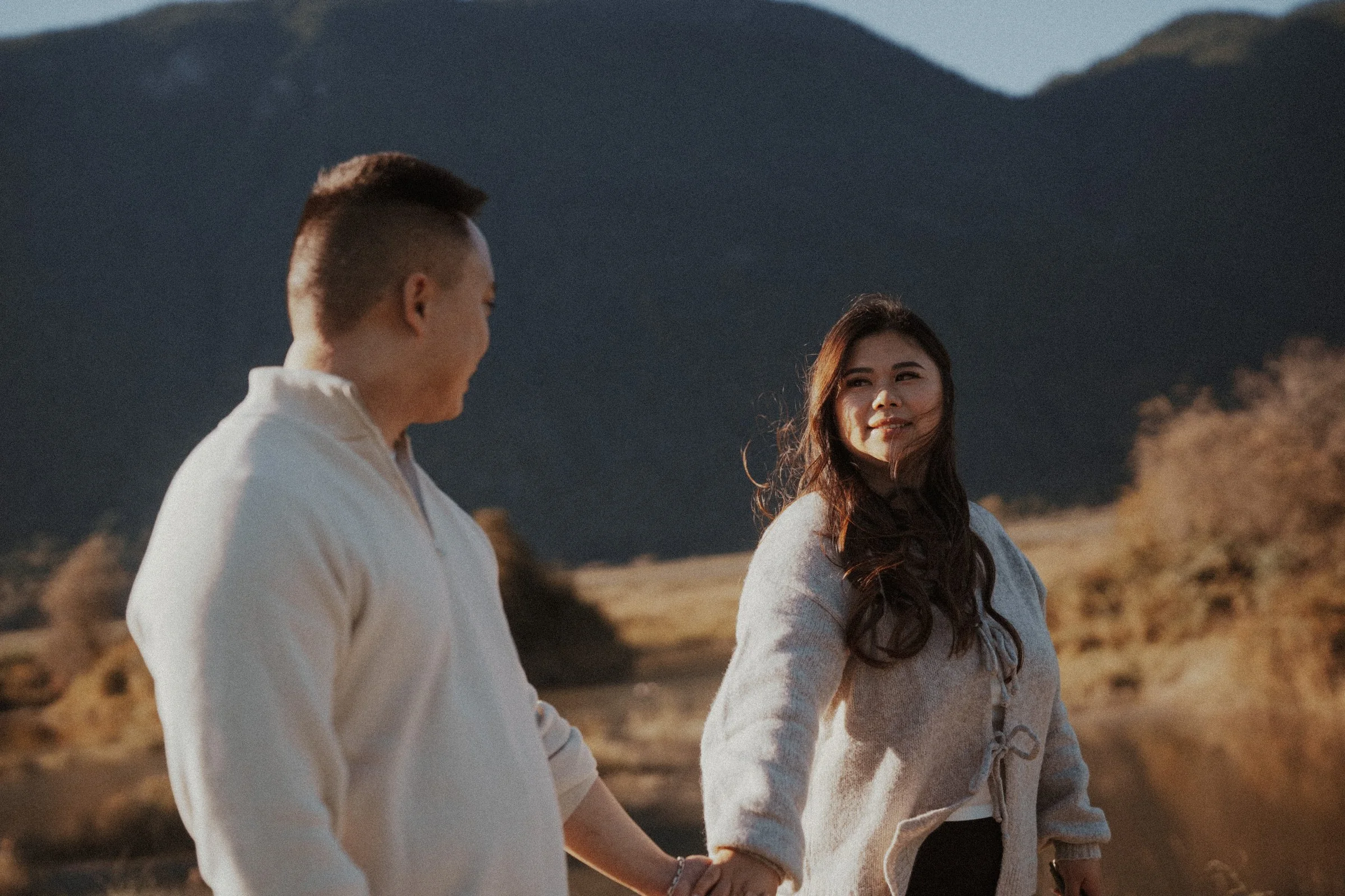 Couple holding hands and looking at each other, Pitt Lake scenery.