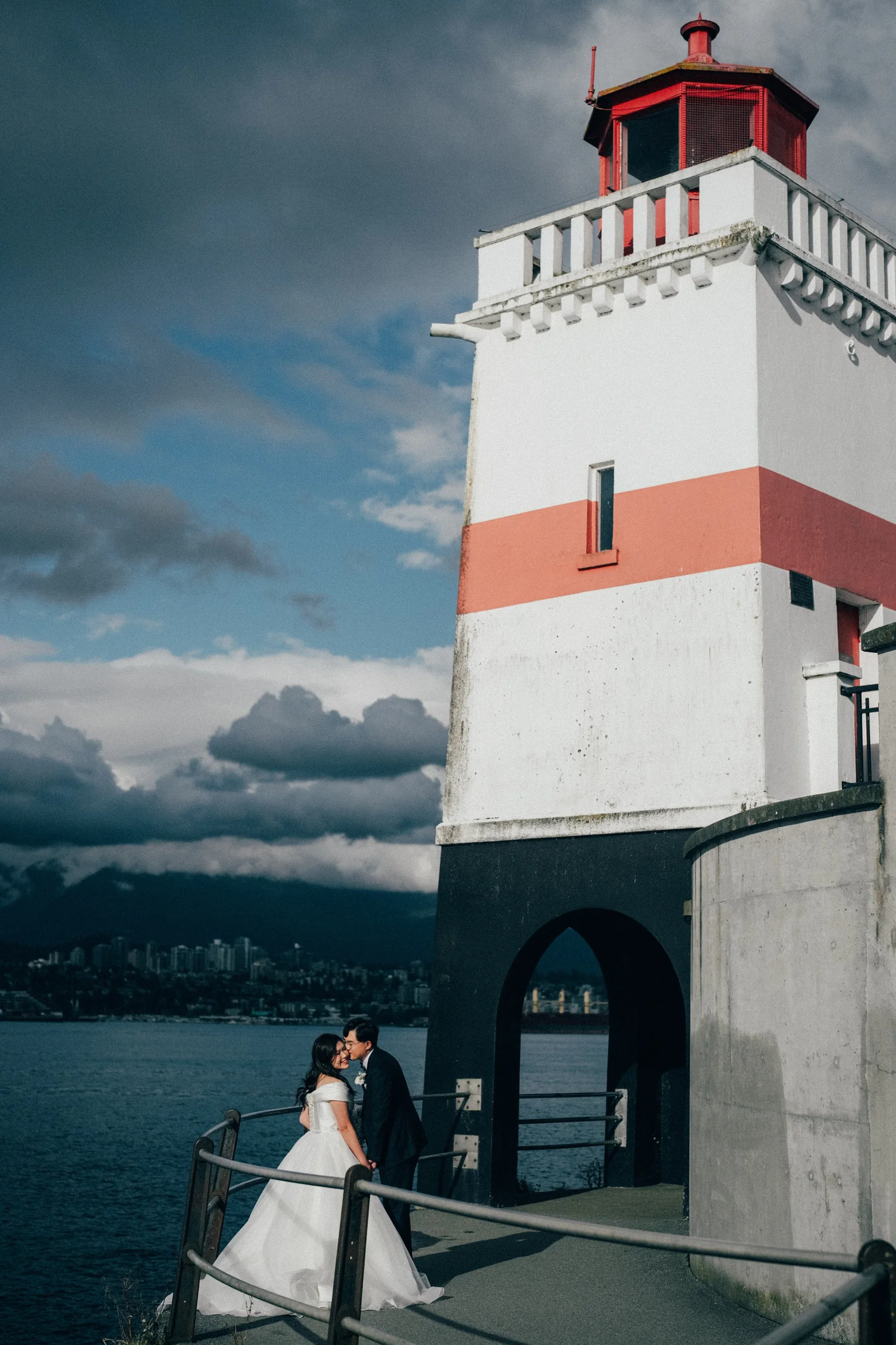 An intimate kiss between the couple next to the iconic Stanley Park Lighthouse and the ocean.