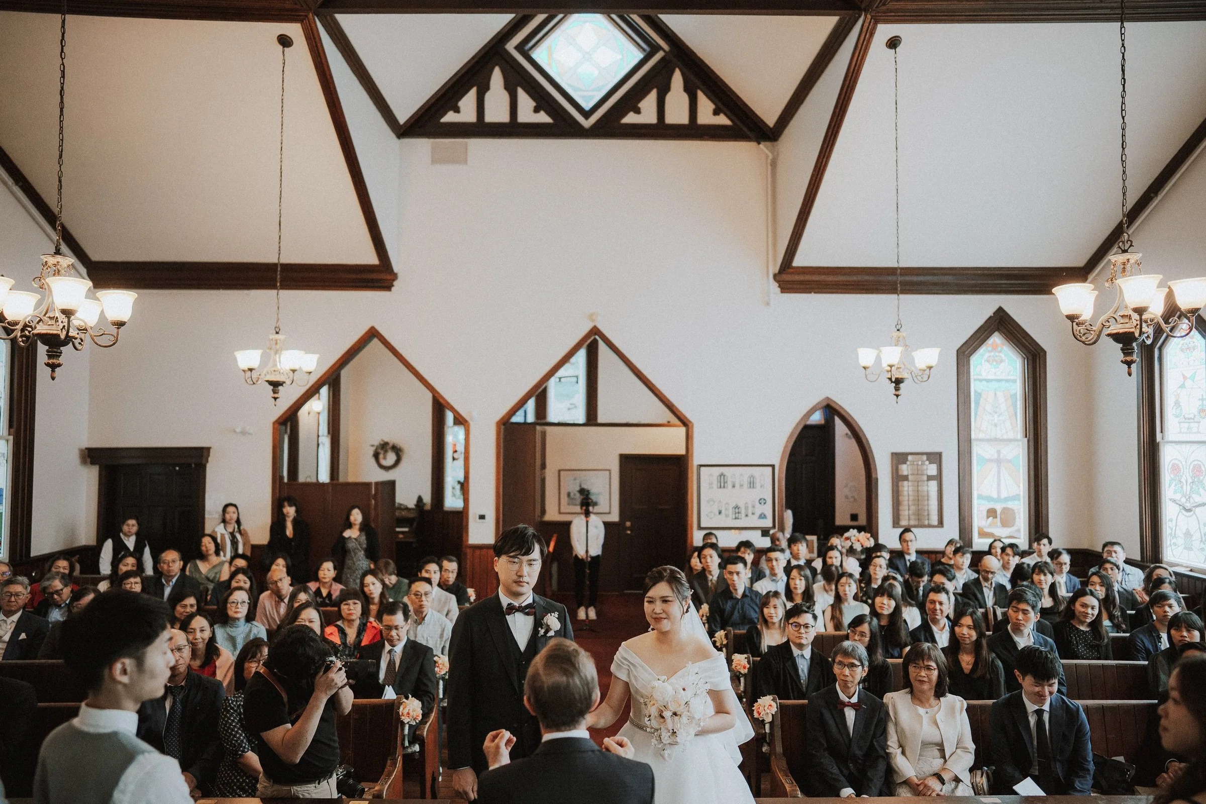 Guests watching the couple's vows beneath the chapel's timber beams.