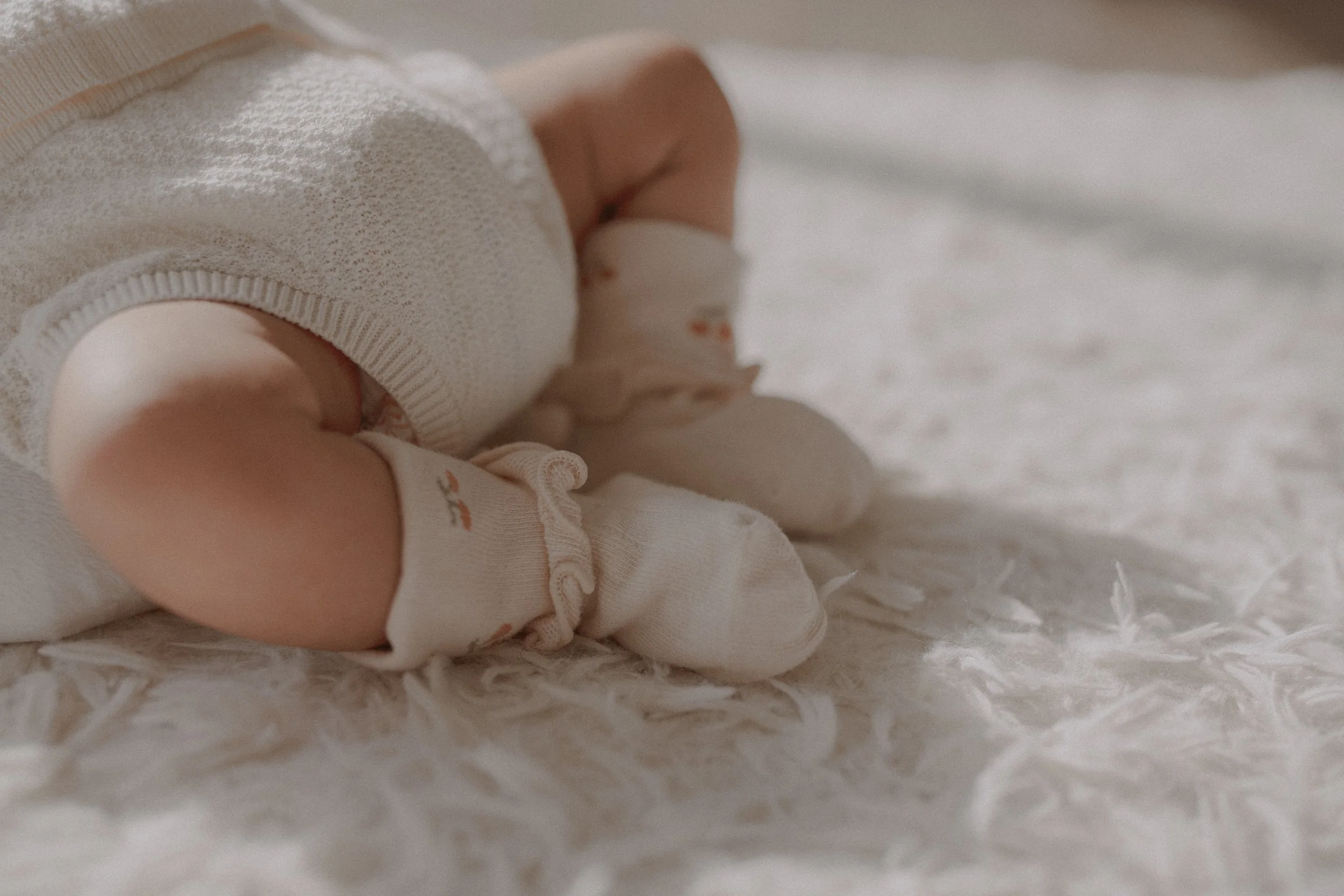 Close-up of a newborn's legs and tiny socks on a textured blanket.