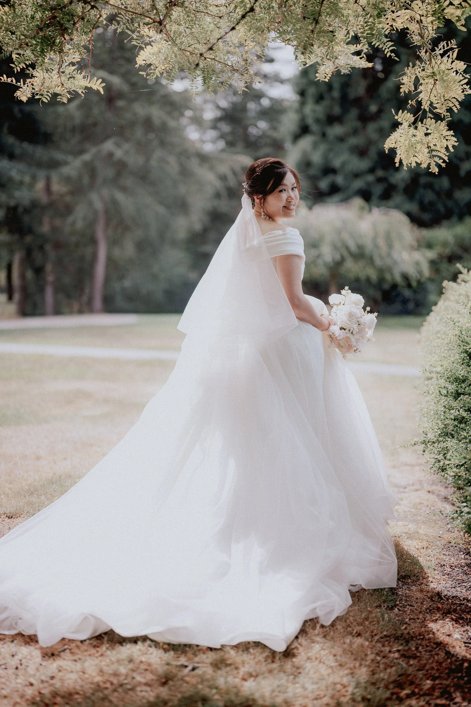 Bride looking back over her shoulder with her long veil and gown trailing behind.