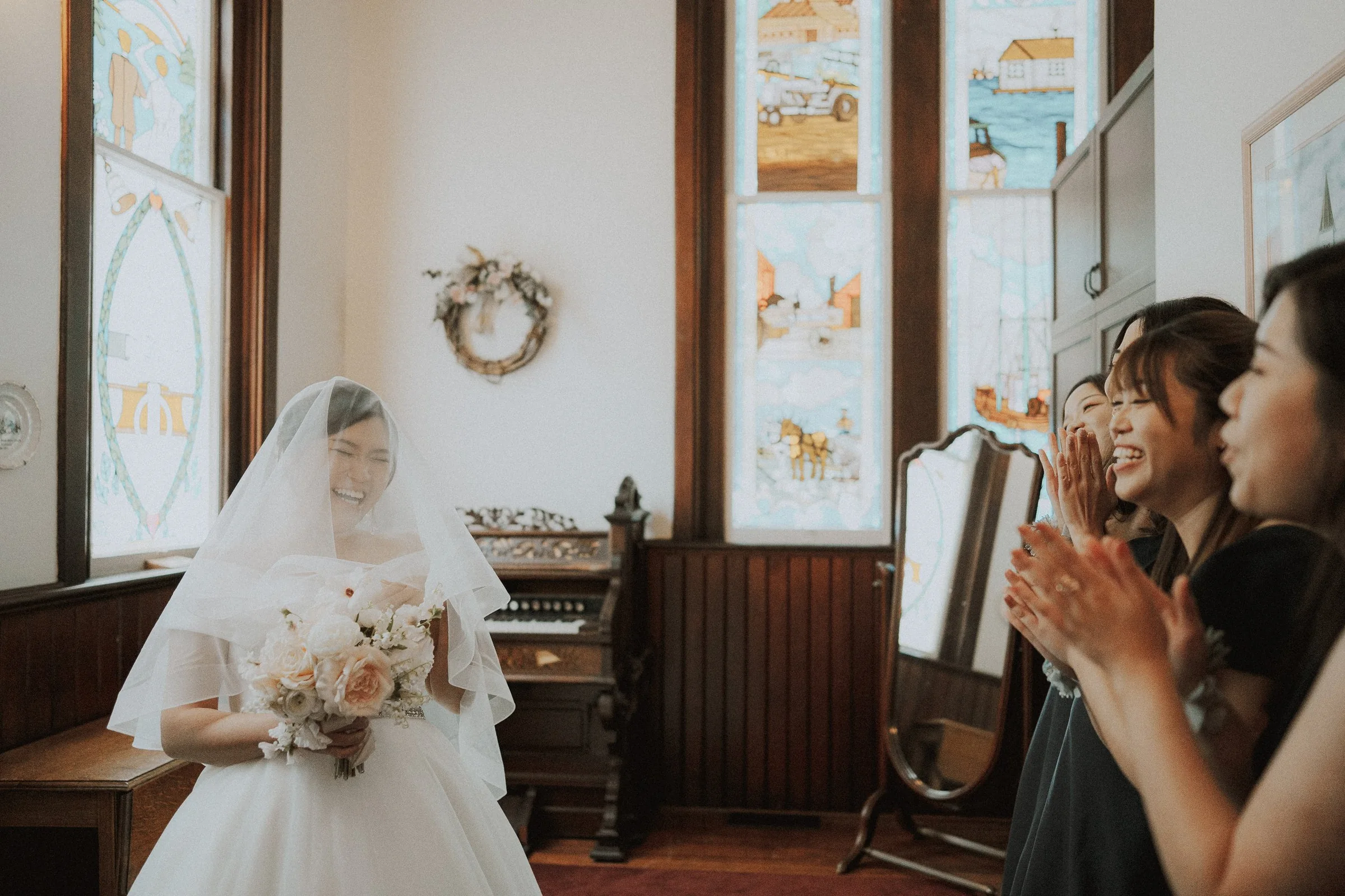 Bride and bridesmaids laughing and clapping in Minoru Chapel bridal room.