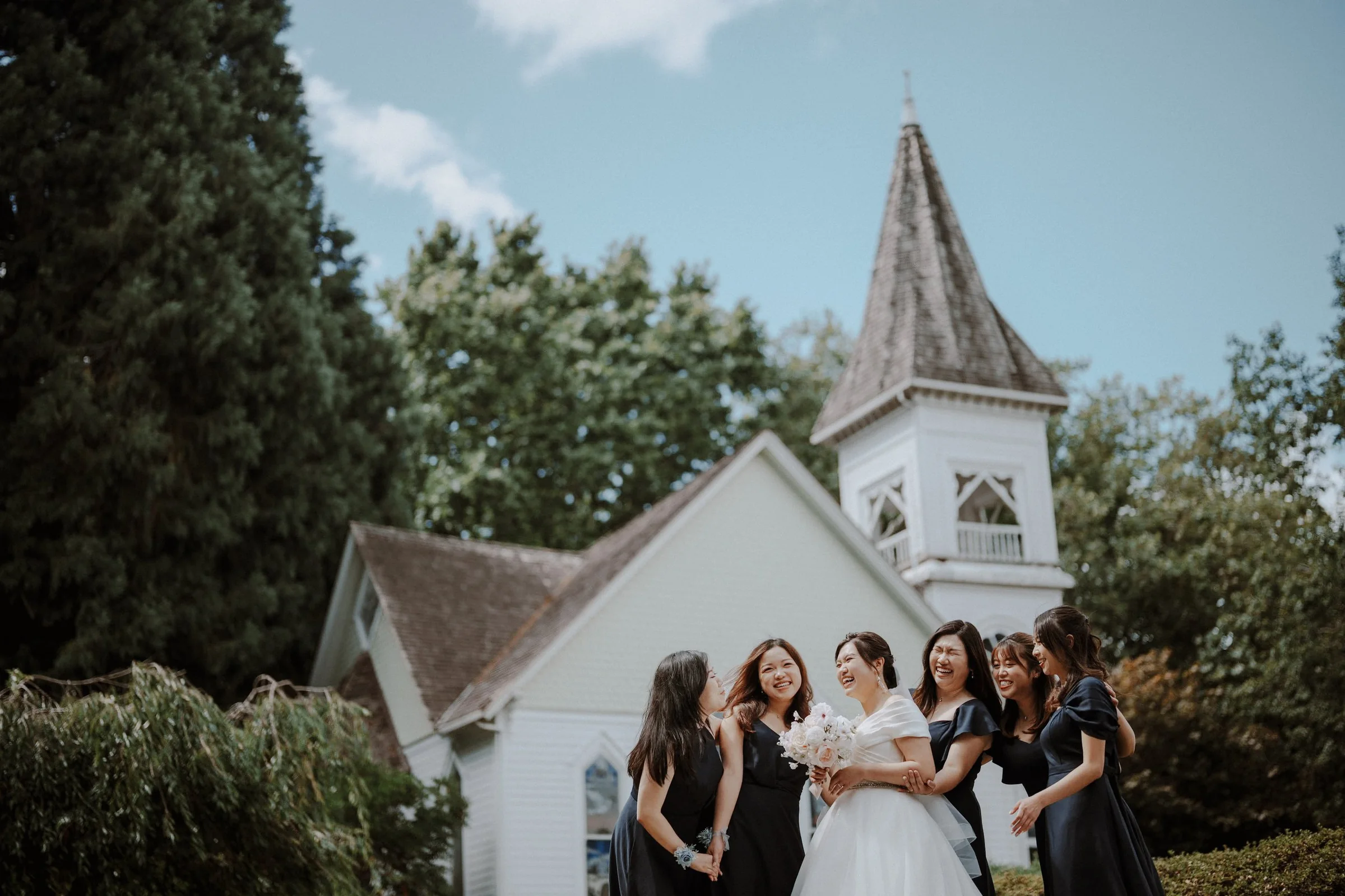 Bridesmaids gathered around the bride and her bouquet in the chapel gardens.
