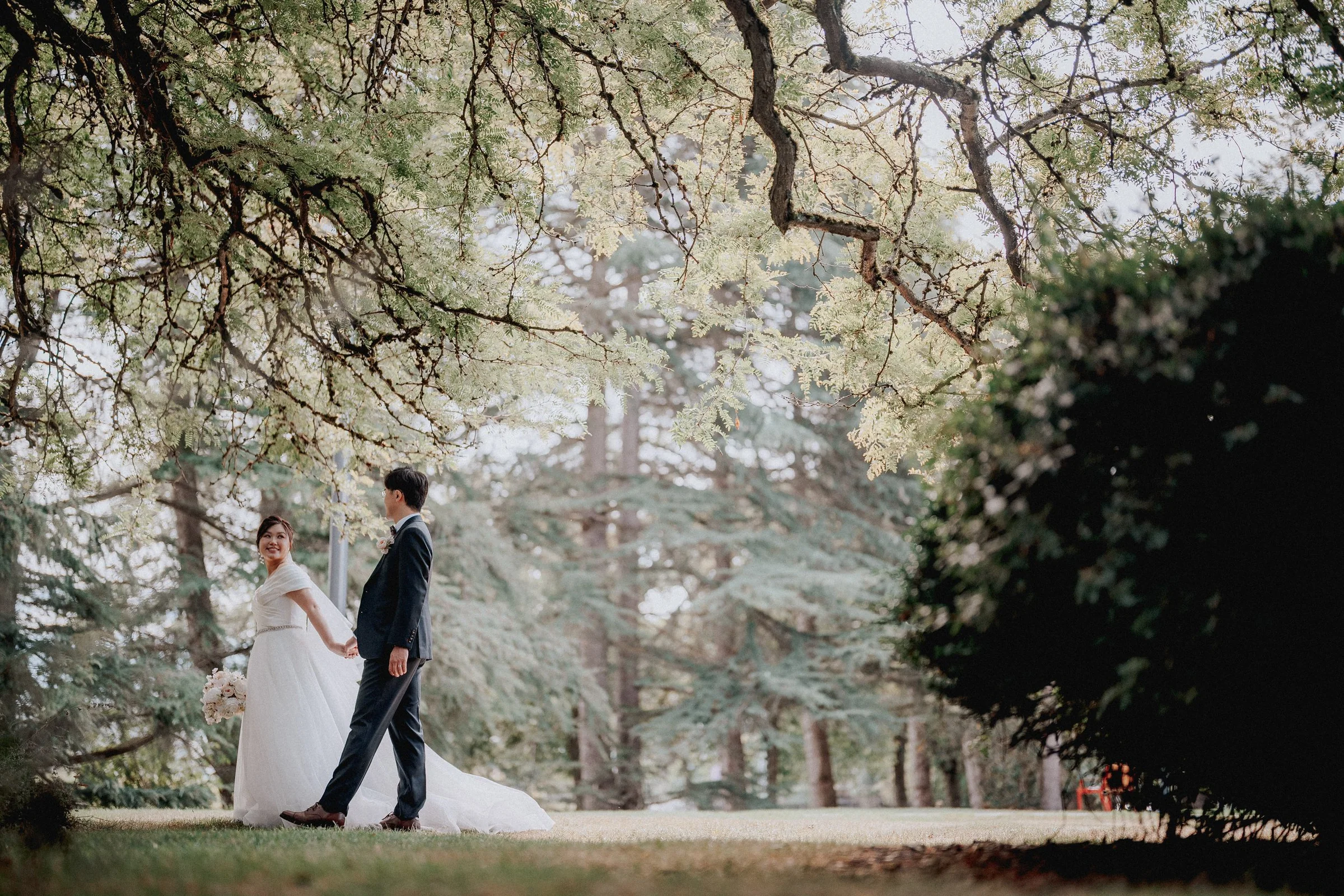 Couple holding hands under beautiful tree canopy, Minoru Chapel outdoor portrait.