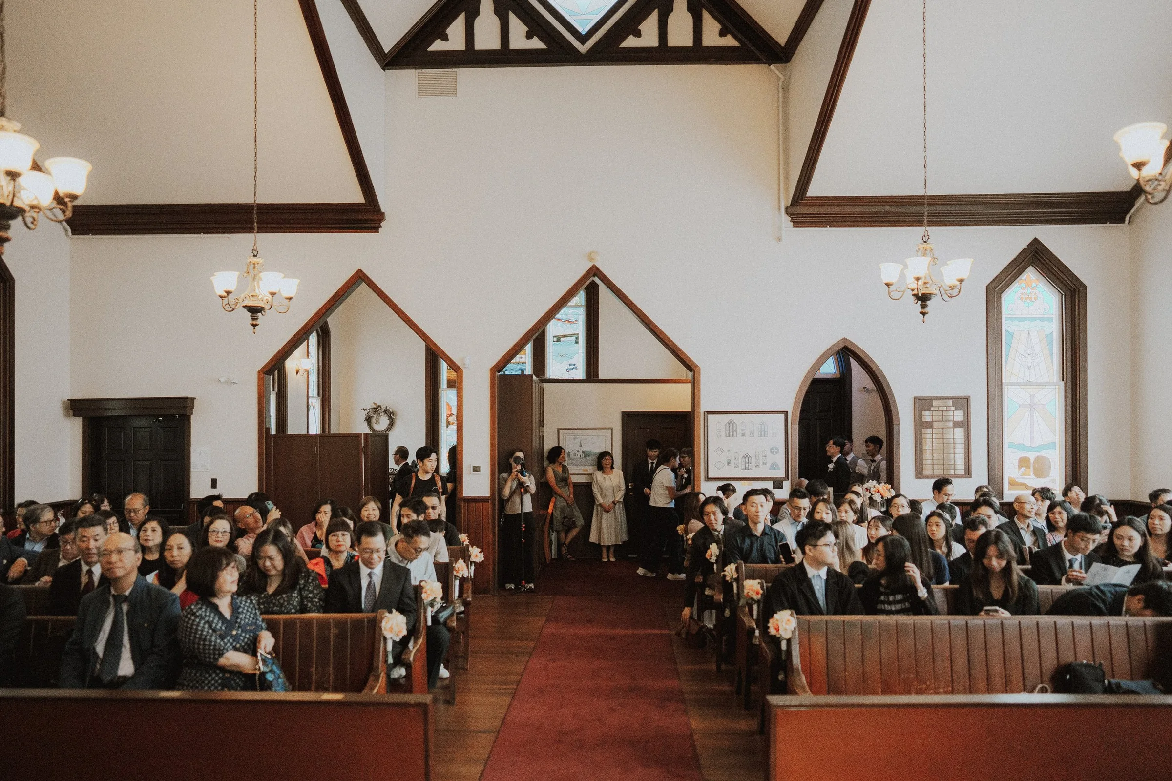 Wide view down Minoru Chapel's central aisle with guests seated on both sides.