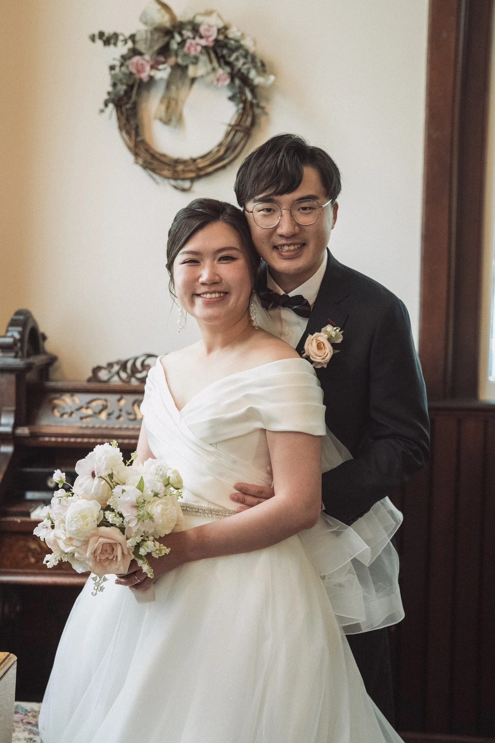 Smiling couple posing together in a softly lit chapel corner.