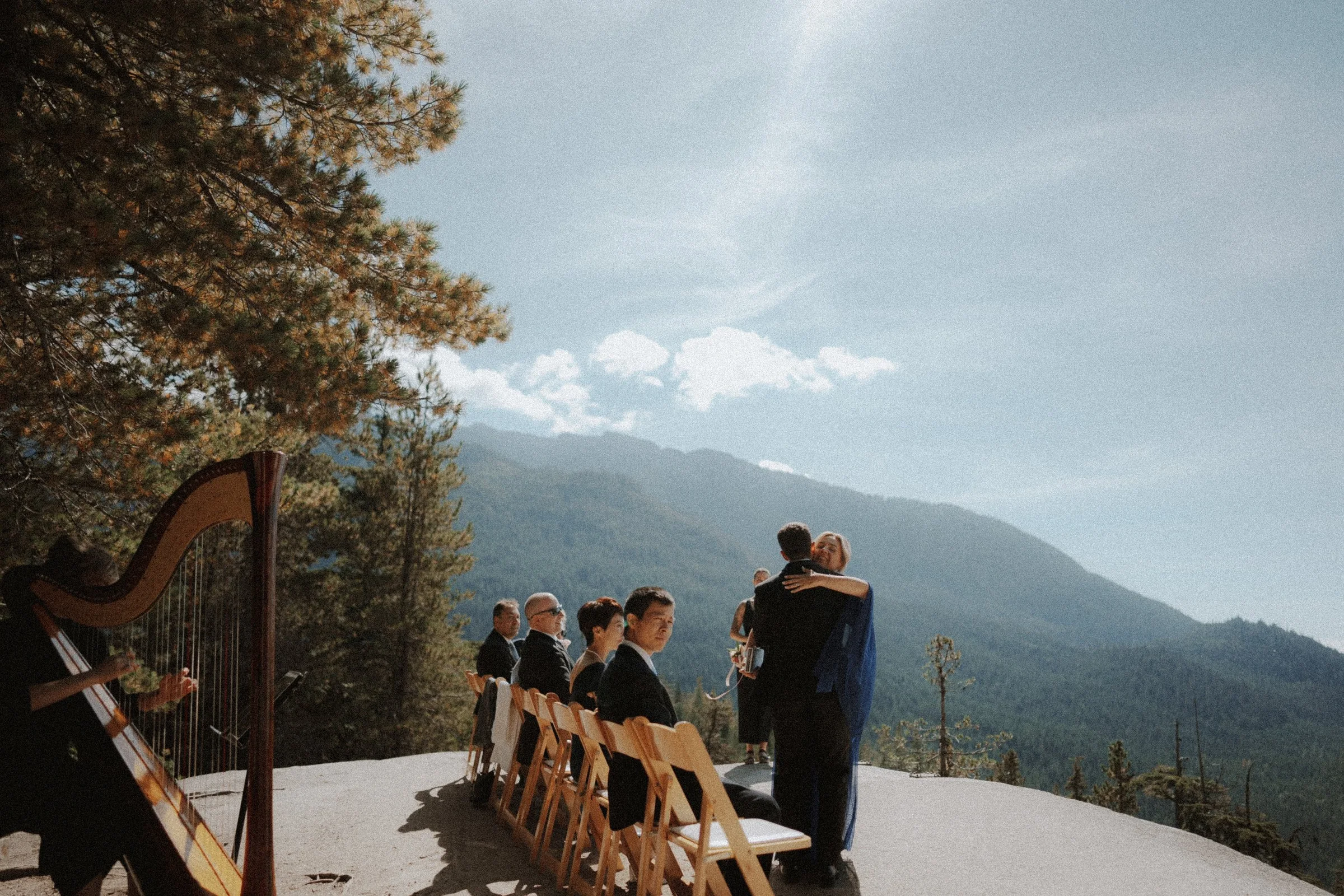 Guests greeting one another beside ceremony chairs and a harp at Sea to Sky Gondola.