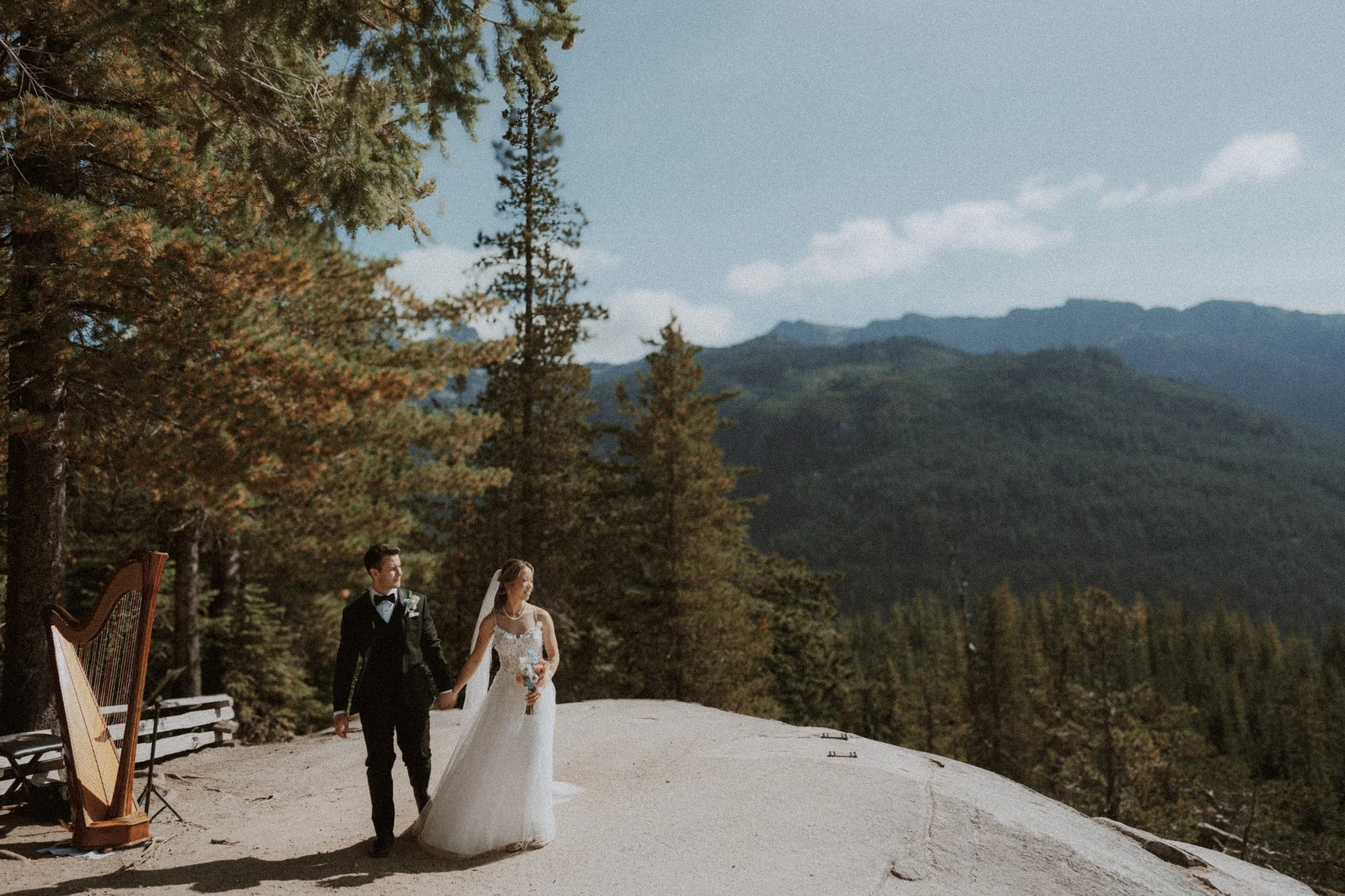Bride and groom standing together on a rocky mountain overlook.
