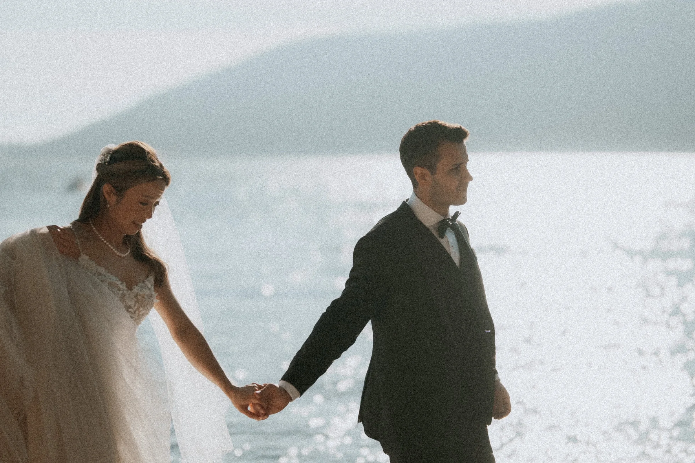 Couple holding hands in bright coastal sunlight.