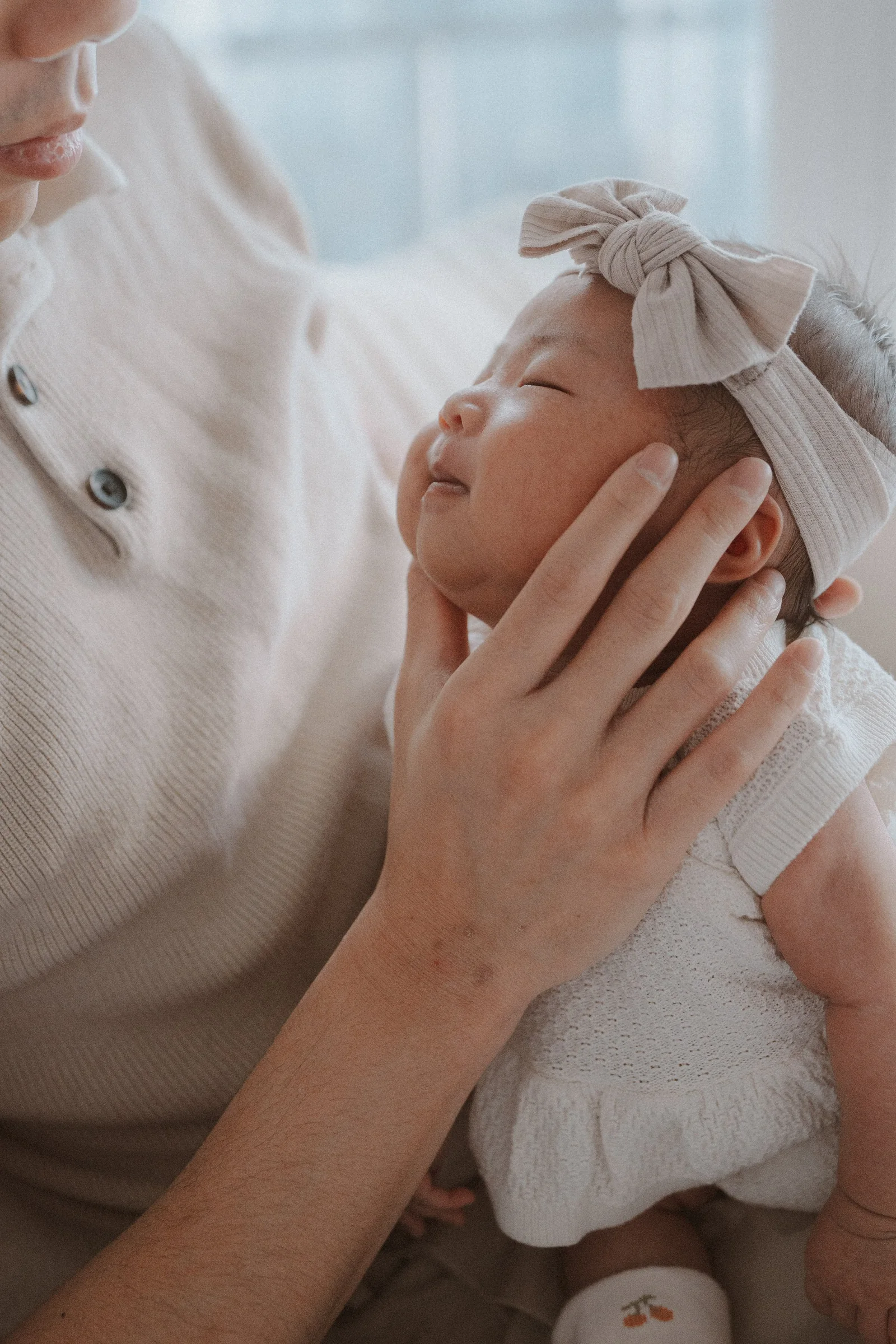 Parent's hand gently supporting a newborn's head during feeding.