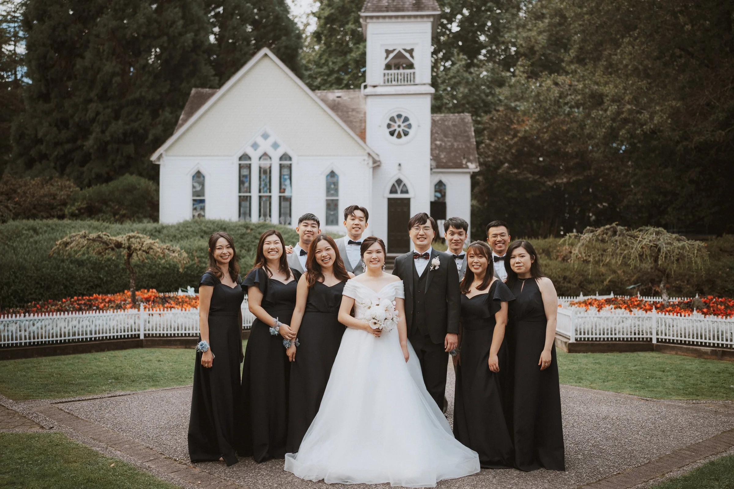 Bride, groom and wedding party posing in front of Minoru Chapel.