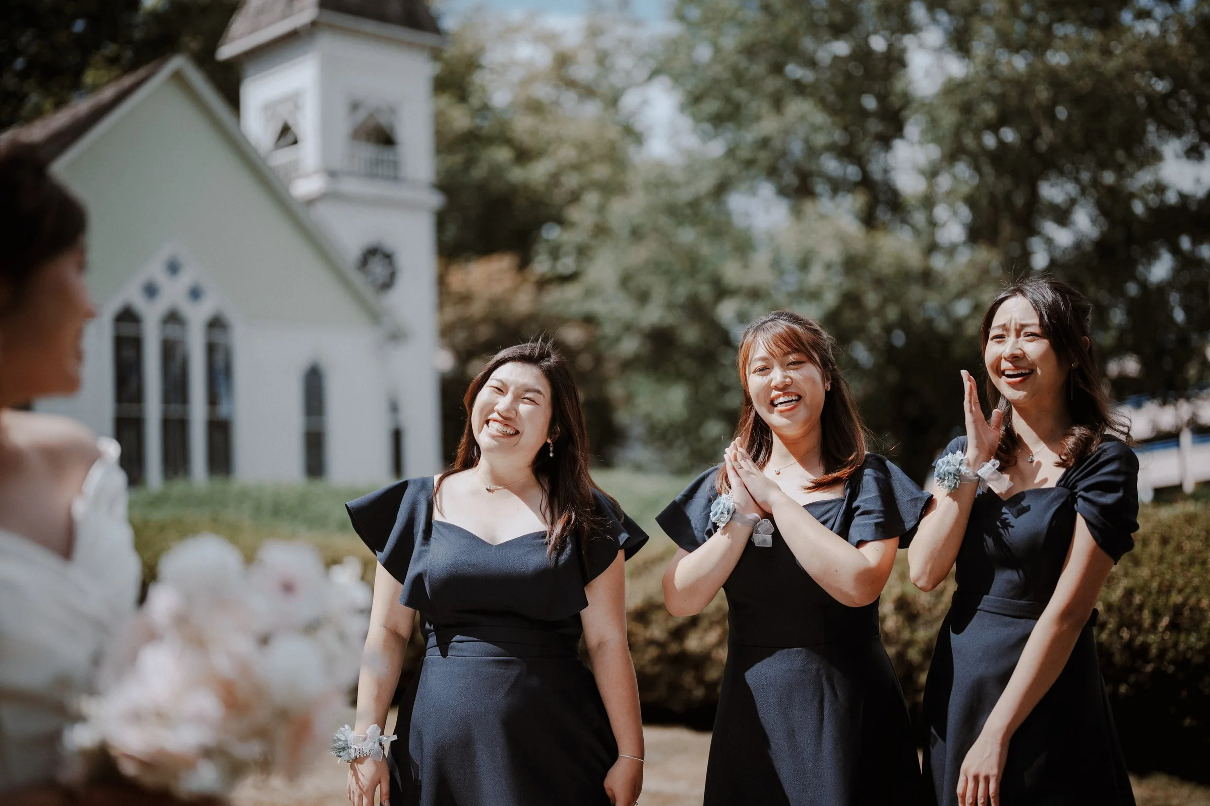Bridesmaids smiling and applauding in the chapel gardens.
