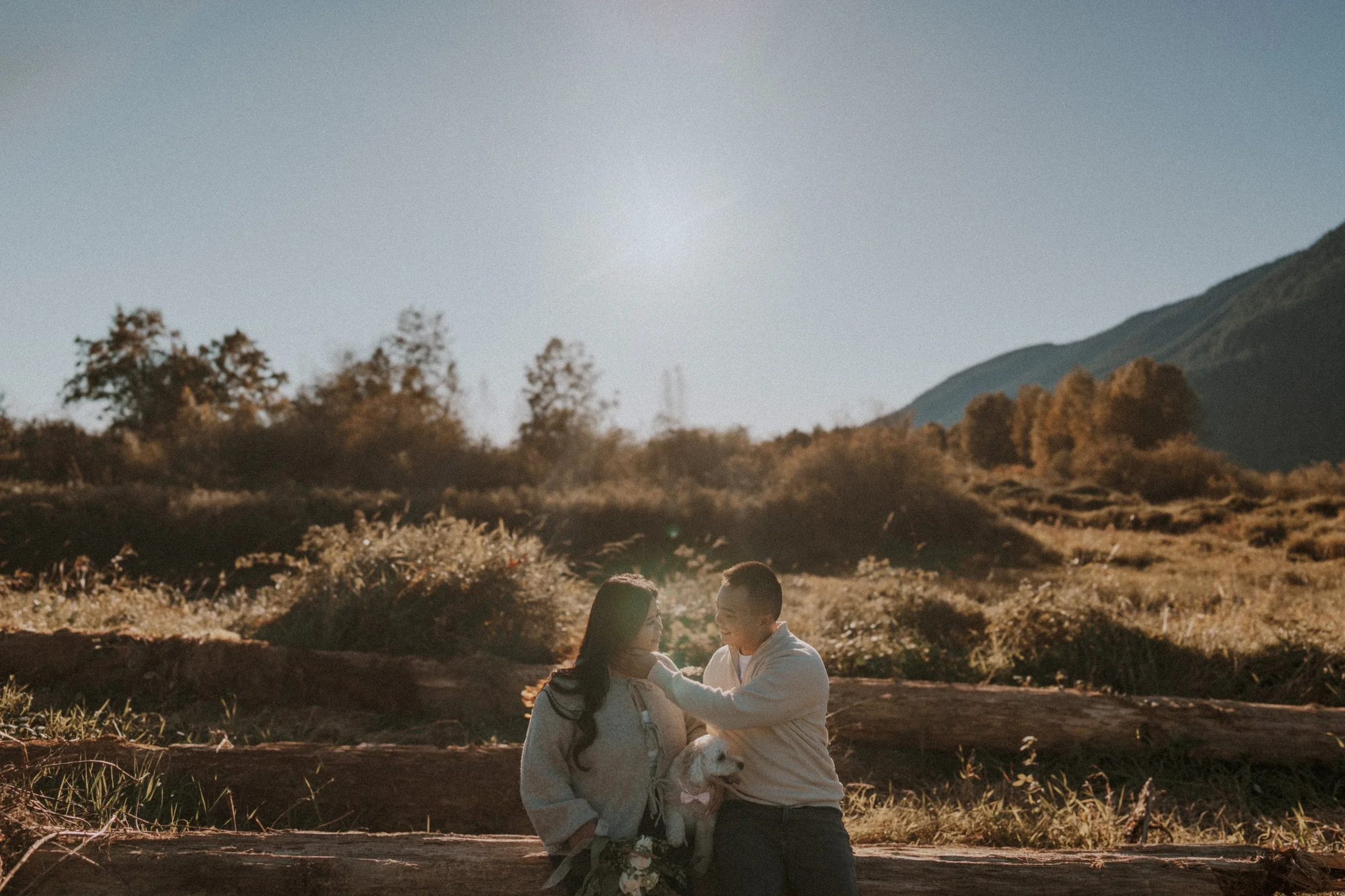 Couple sitting with dog on bench, intimate portrait, pet-friendly Pitt Lake.