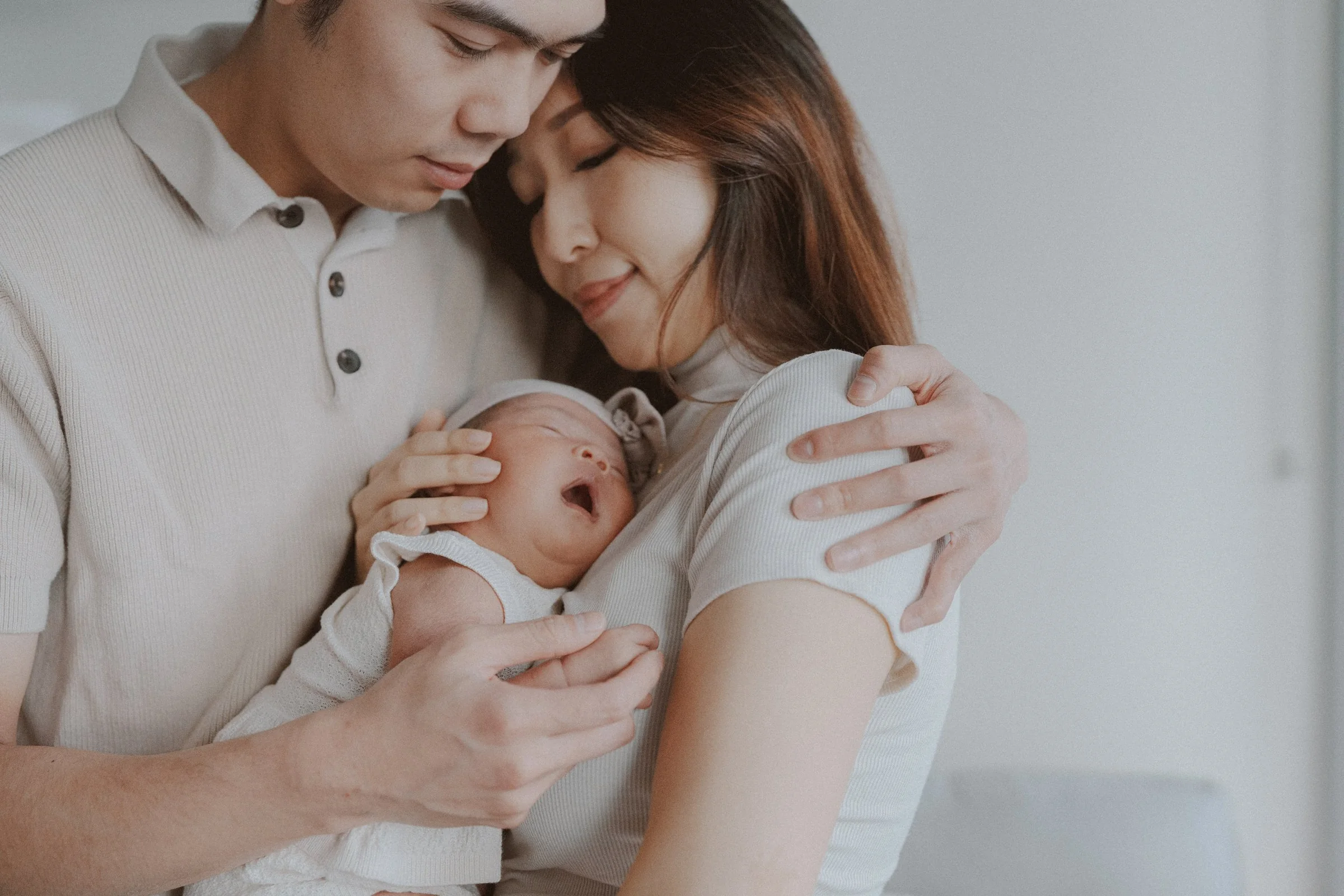 Parents embracing with their newborn held between them.