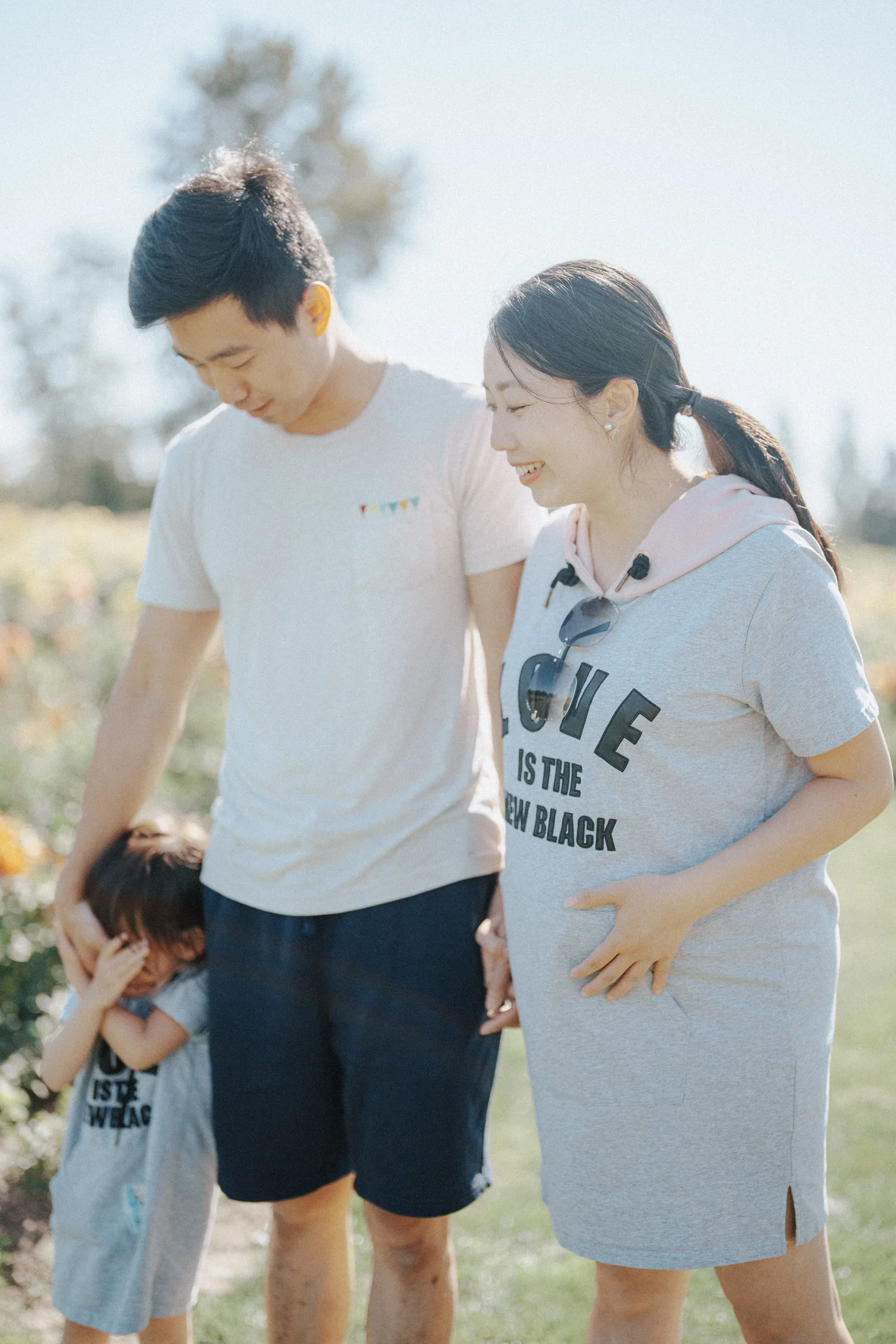 Family standing outdoors with child covering face at Richmond Country Farms