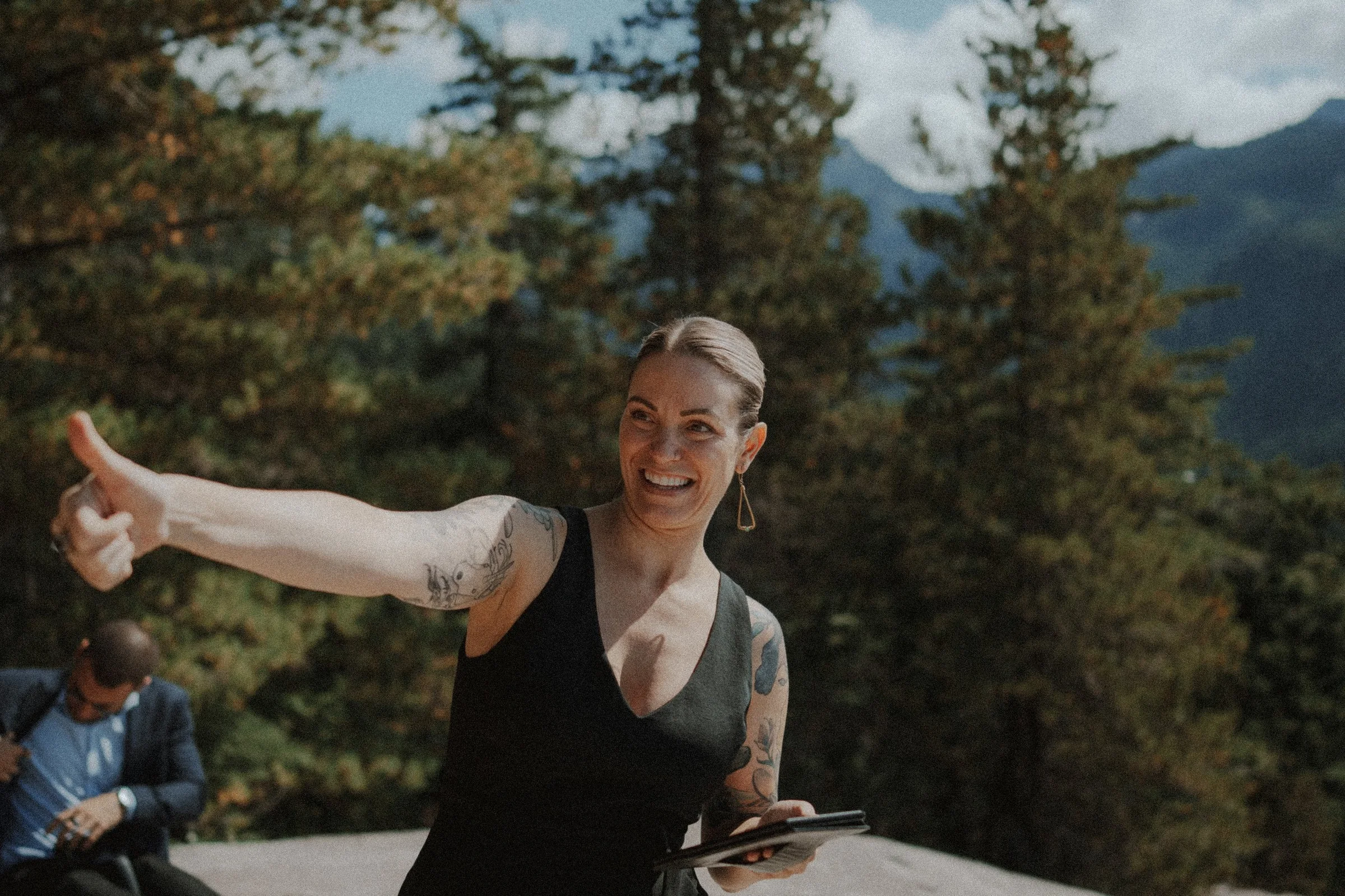 Smiling guest gesturing toward the mountain wedding ceremony area.