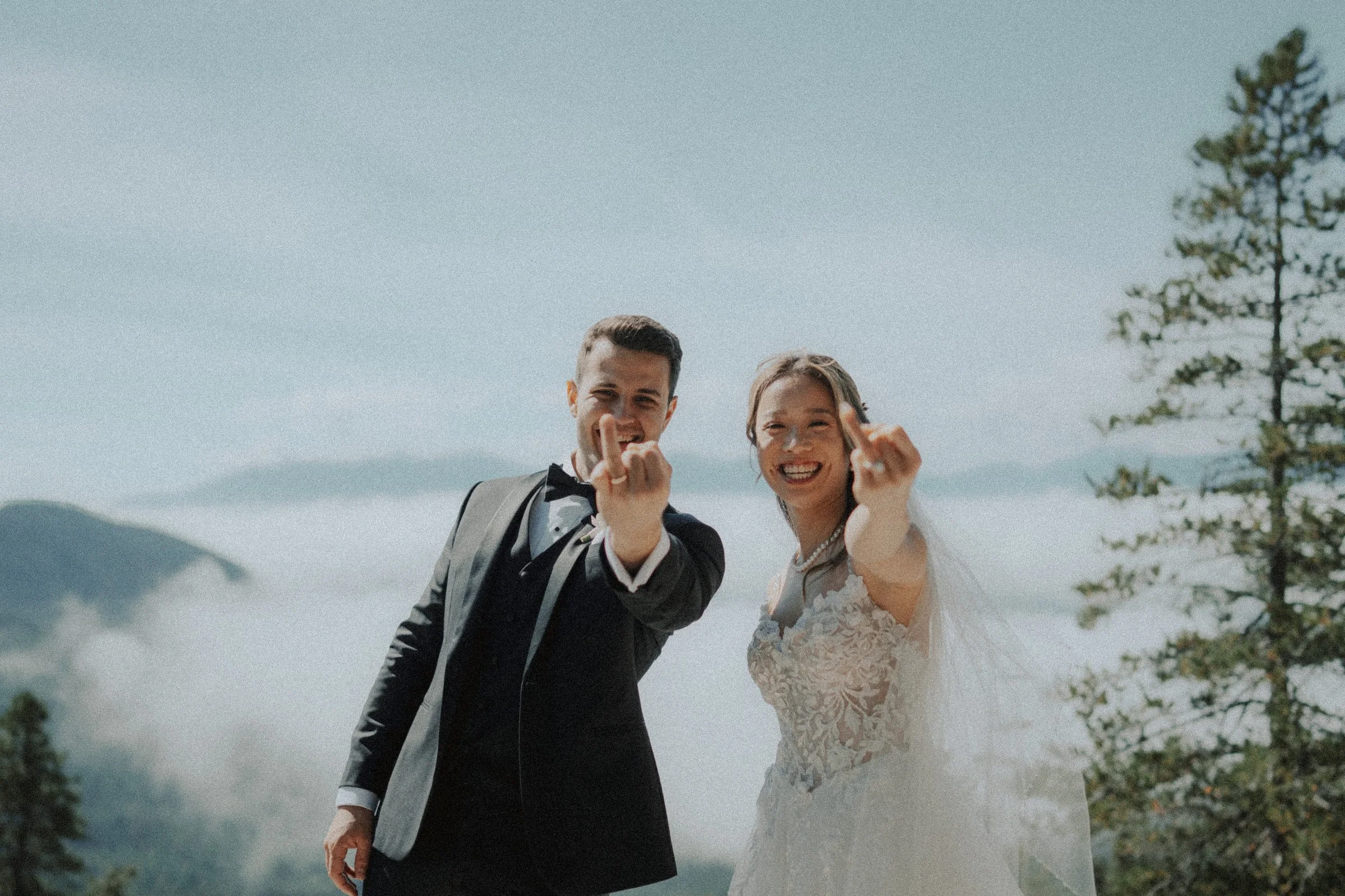 Bride and groom smiling as they hold up their wedding rings.