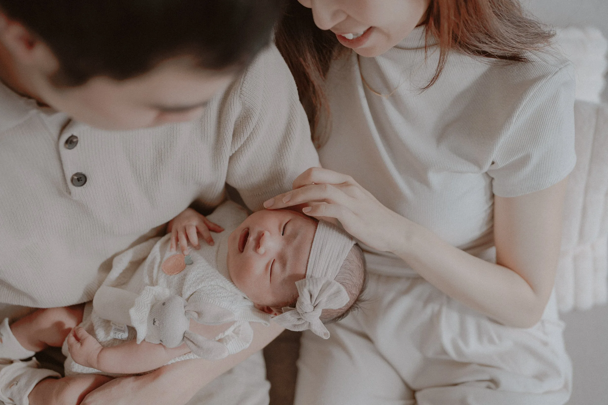 Parent soothing a newborn lying across the other parent's lap.