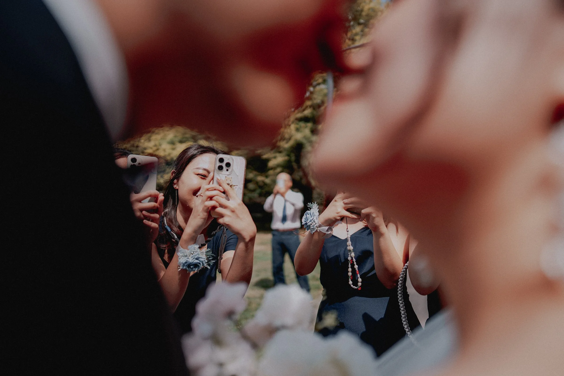Wedding guests taking photographs with their phones near the couple.