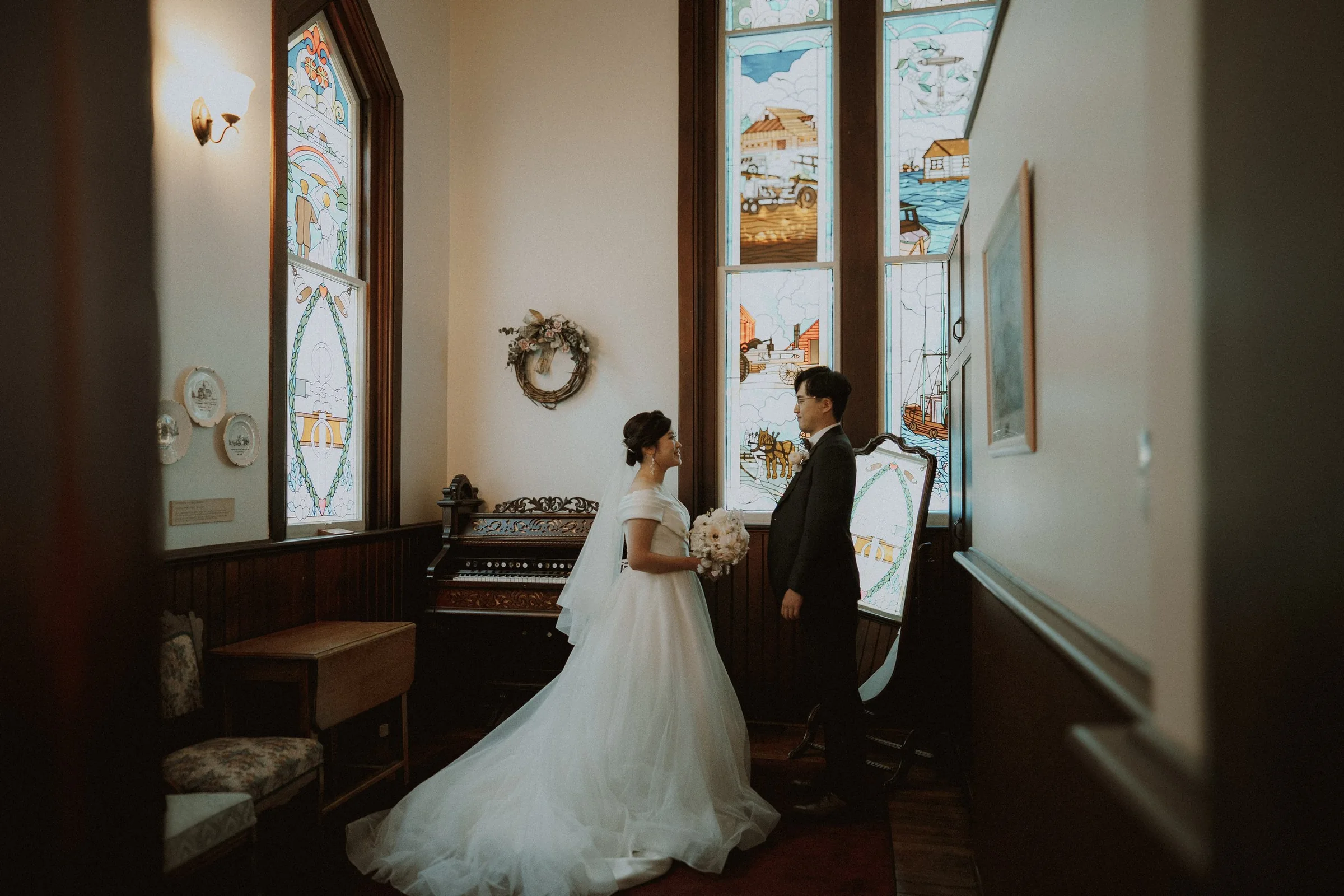 Bride and groom standing together beside Minoru Chapel's stained-glass windows.