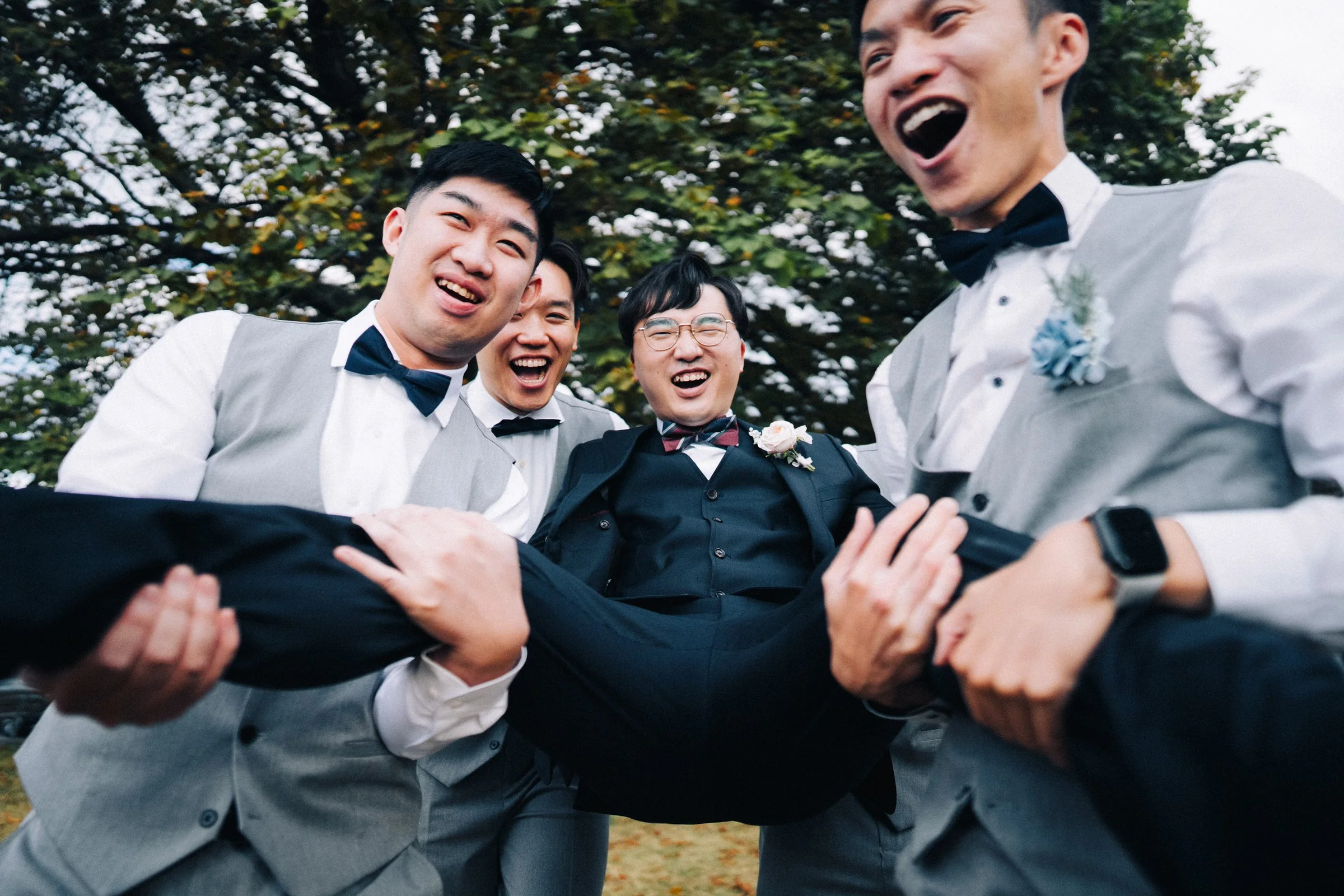 Pure fun! The groom is lifted and cheered by his groomsmen in a loud, happy celebration.